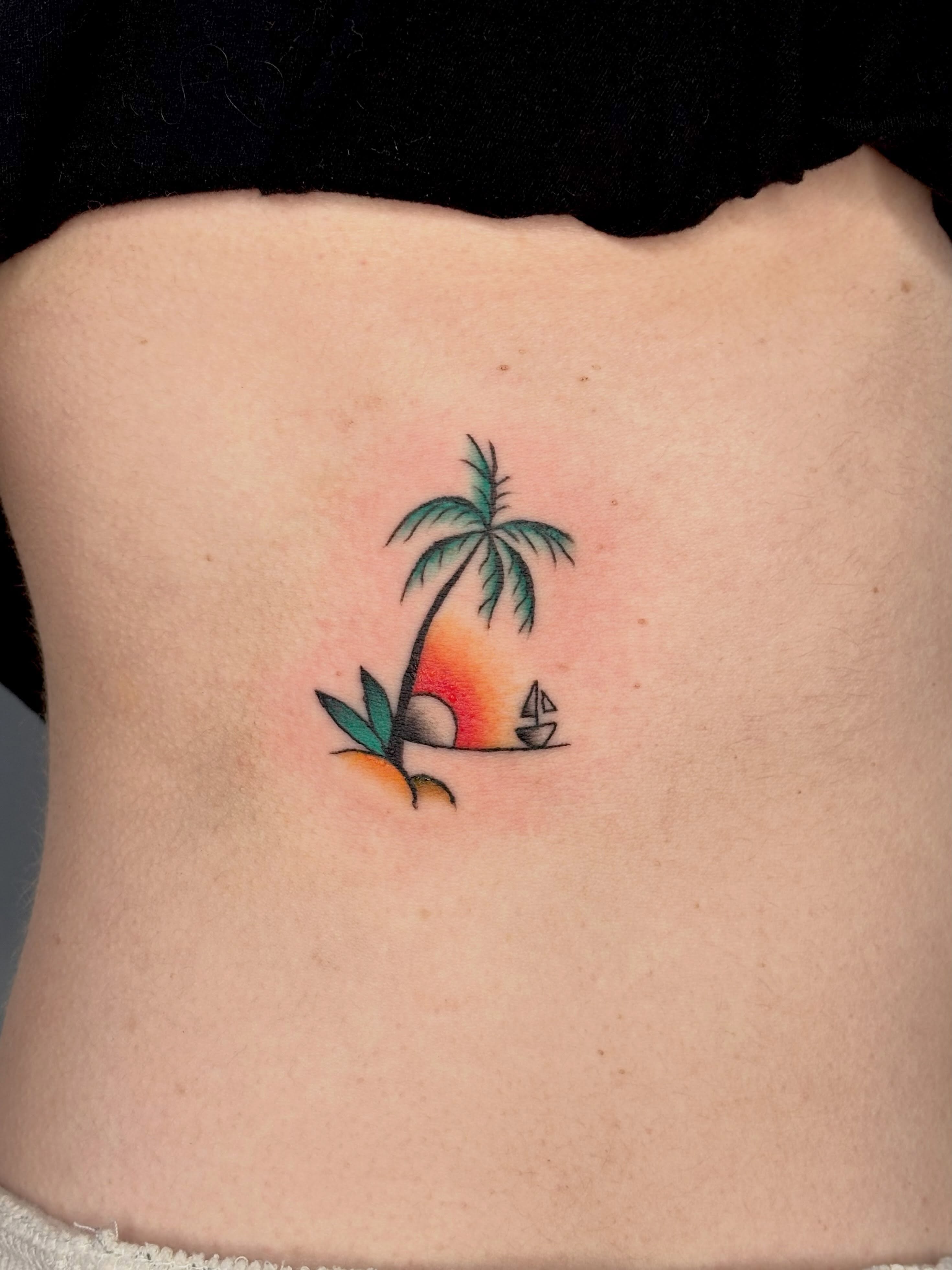 Sunset with palm tree and sailboat American traditional tattoo on the ribs by Topher Belmont