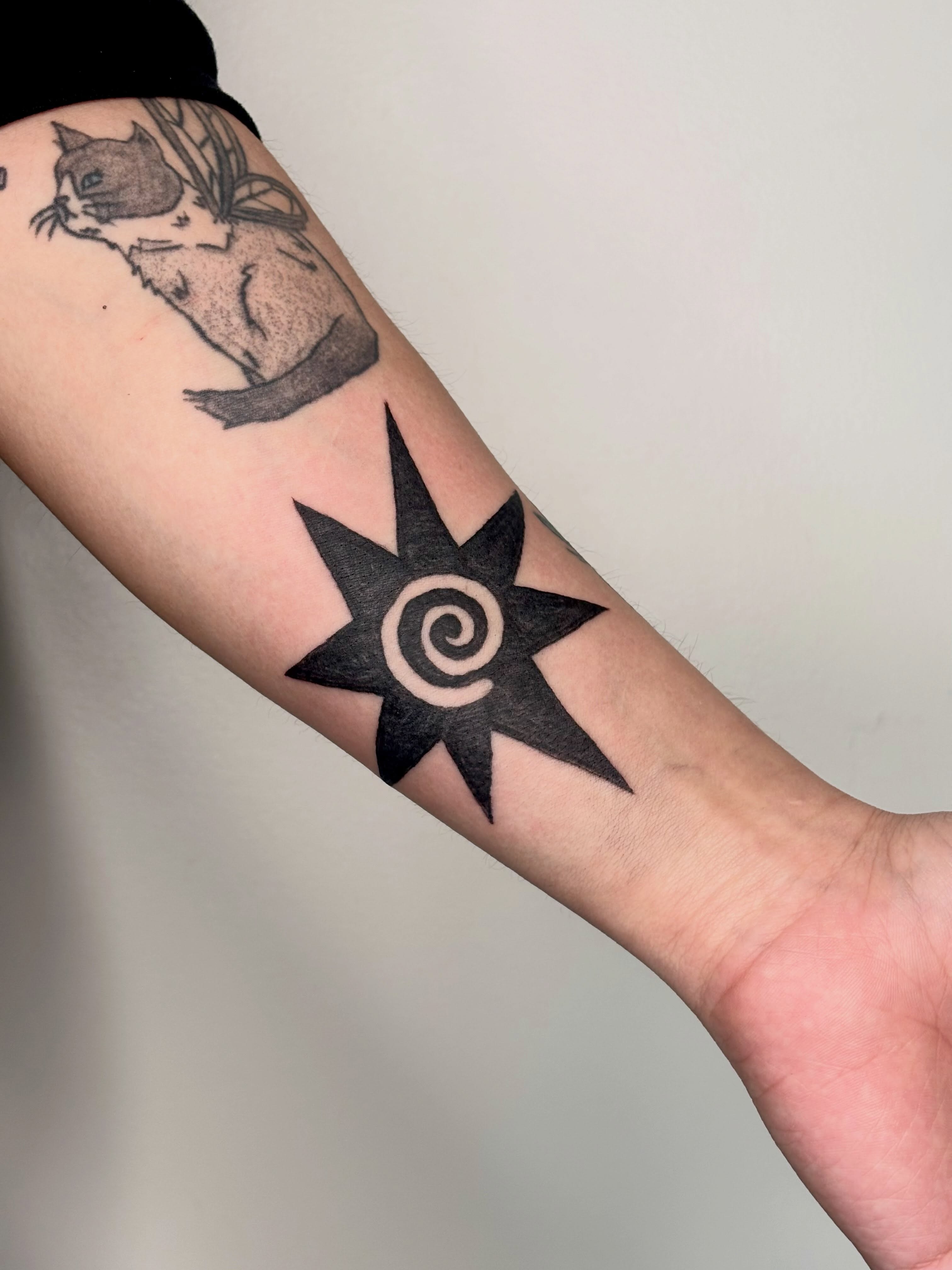 Sun with spiral geometric tattoo on the forearm by Topher Belmont