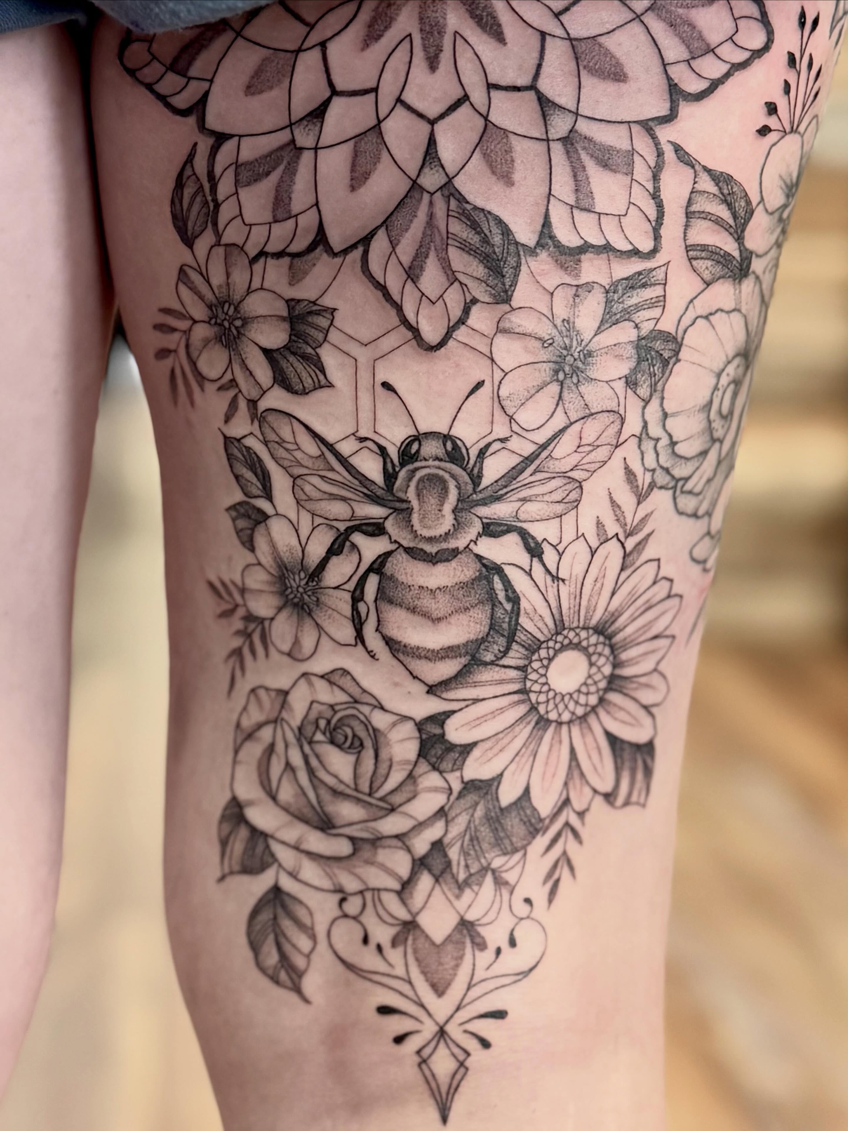 Bee and floral bouquet geometric tattoo on the thigh by Katie Stacy