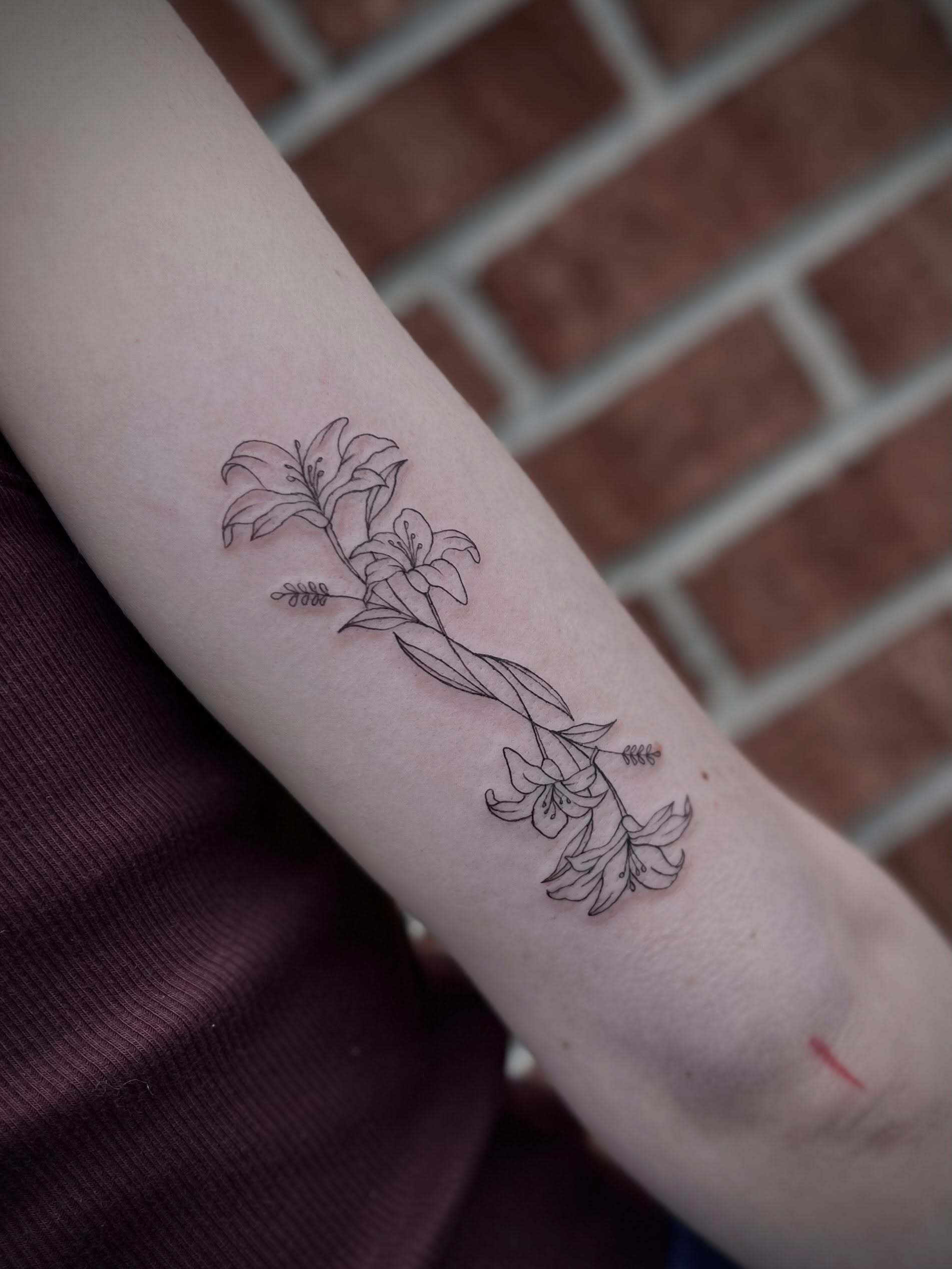 Lilies fine line tattoo on the forearm by Lexi Rose