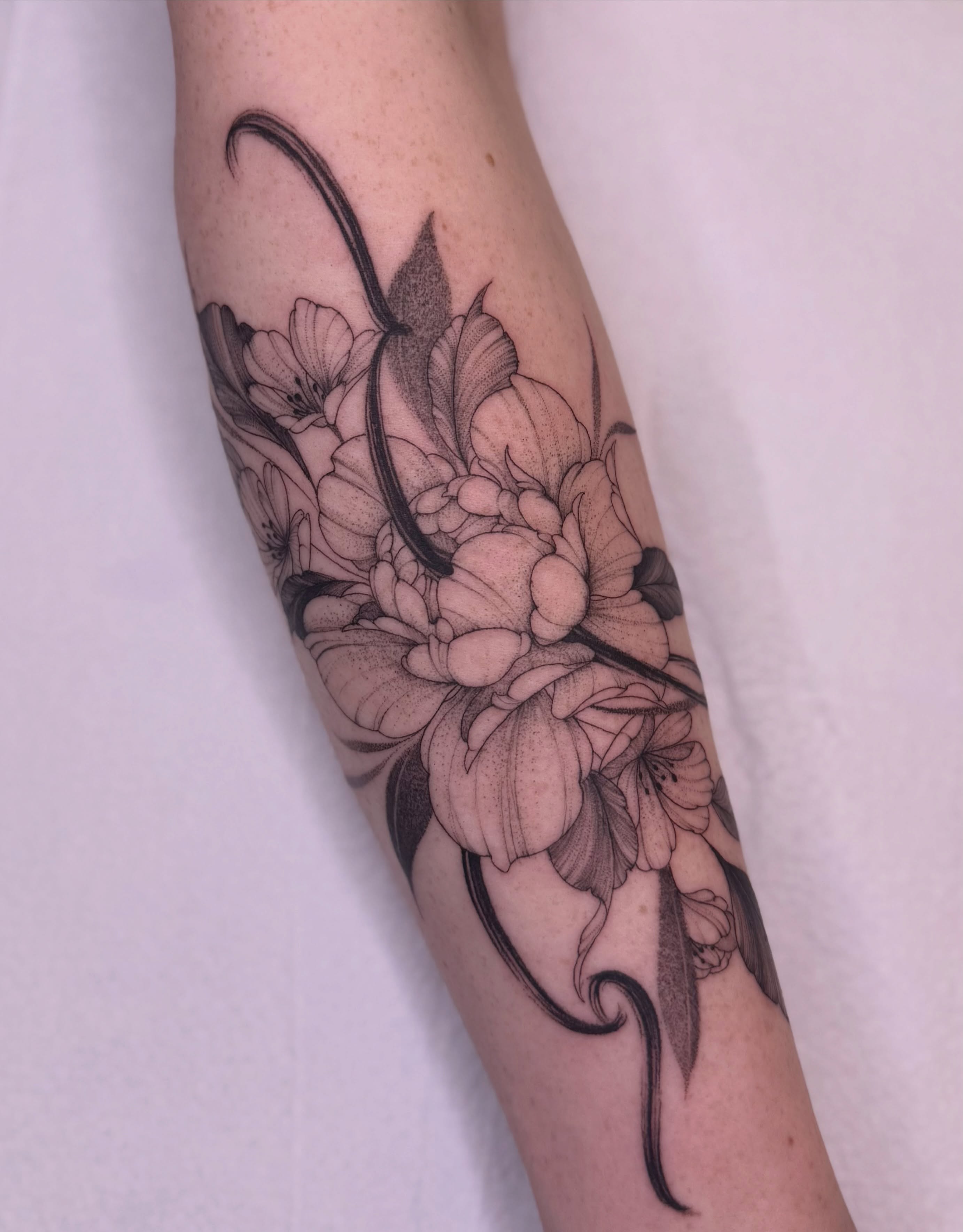Floral arrangement black and grey tattoo on the forearm by Jena Perry