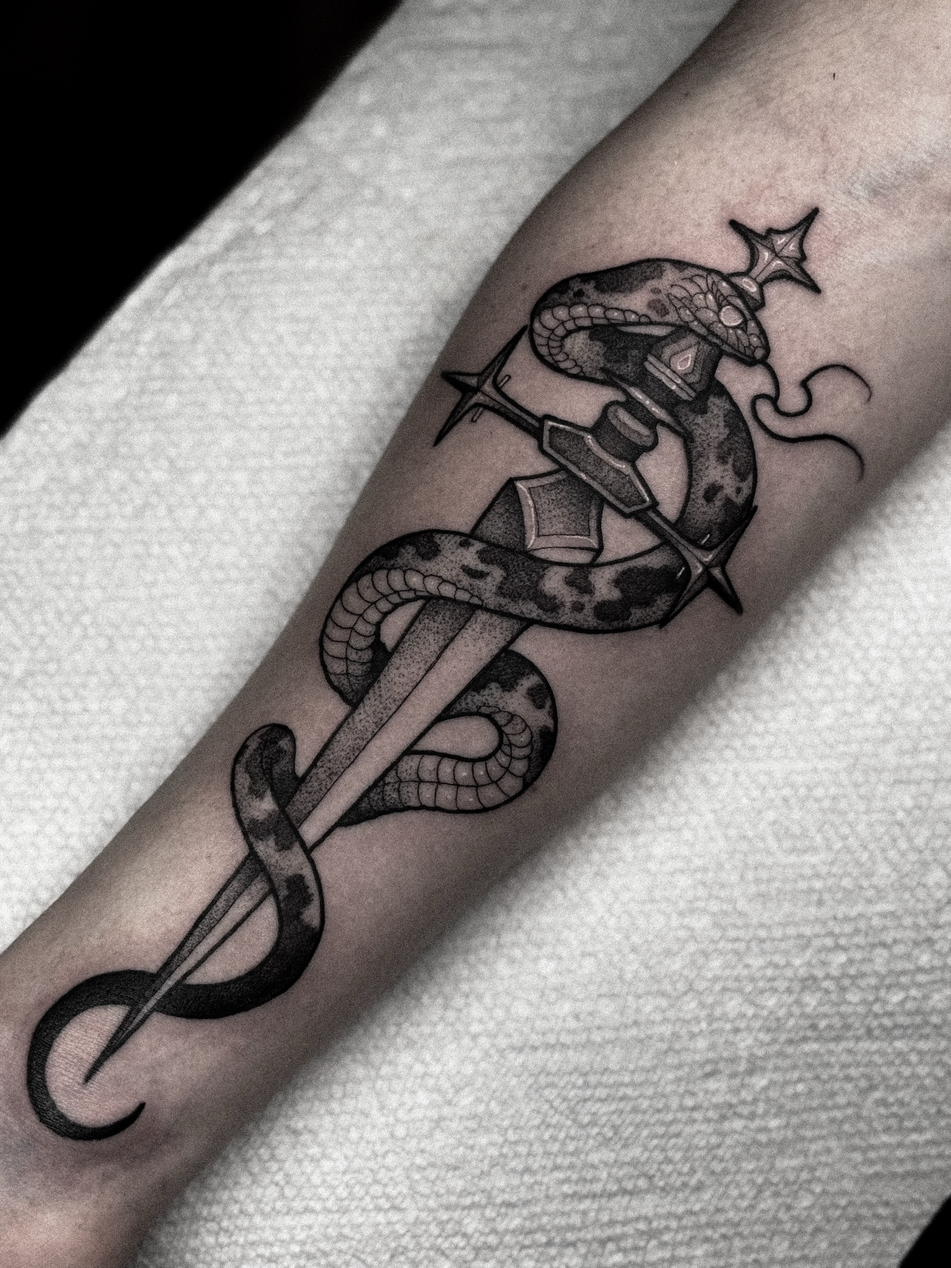 Snake and dagger black and grey tattoo on the forearm by Dane Bezeau