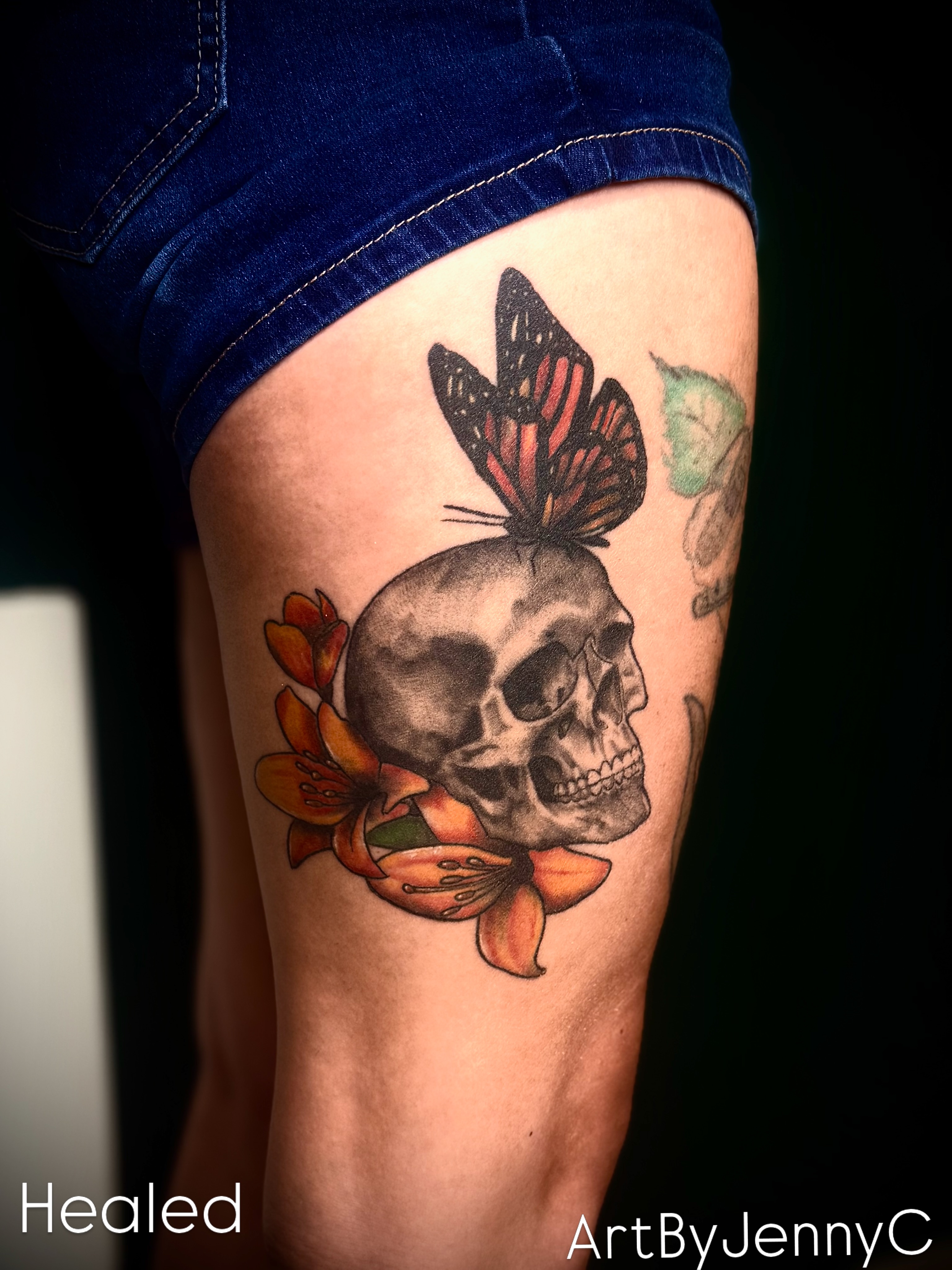 Skull with butterfly American traditional tattoo on the thigh by Jennifer Contreras