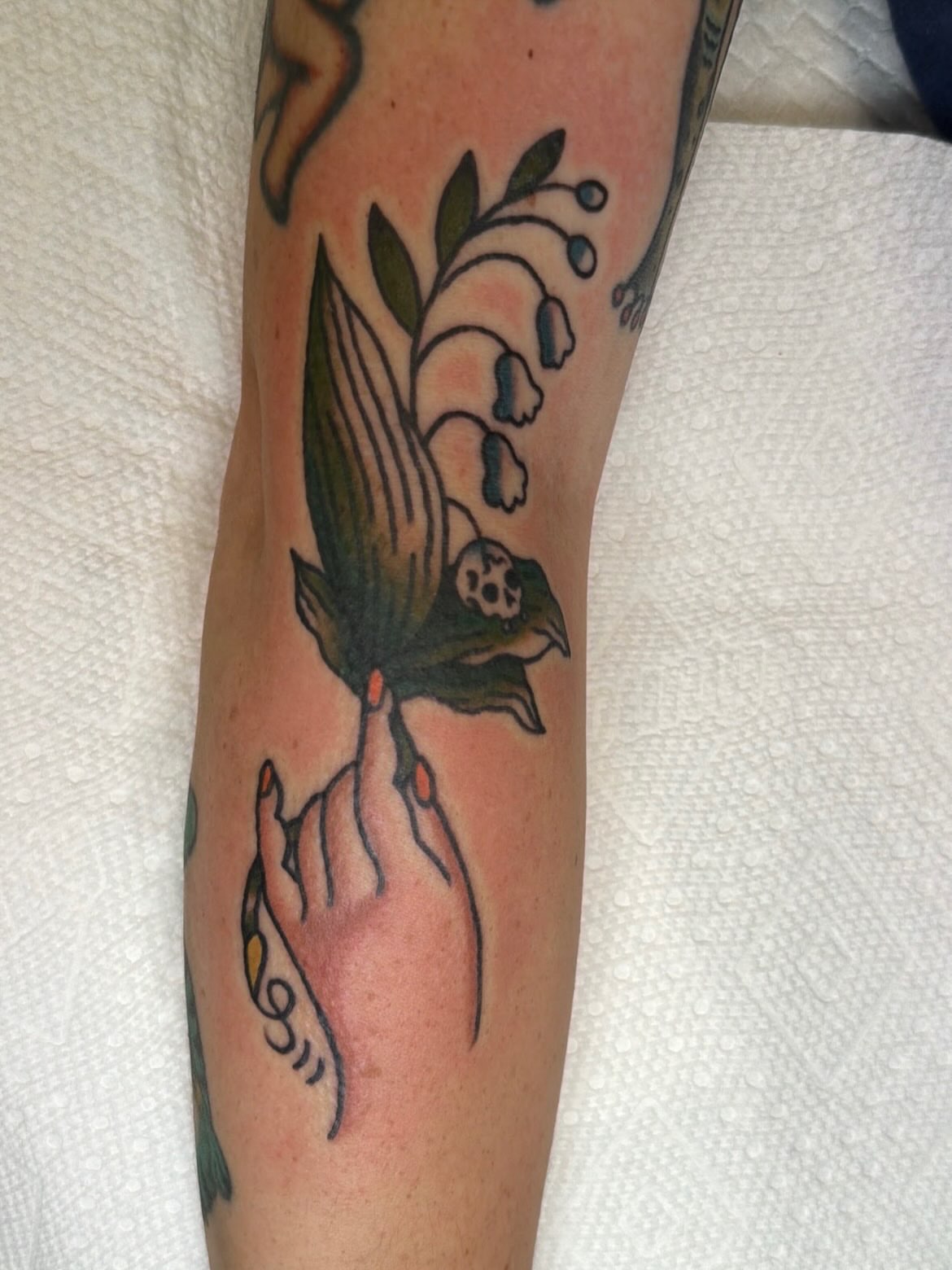 Bird and lily of the valley American traditional tattoo on the forearm by Emma Fox Tattoo