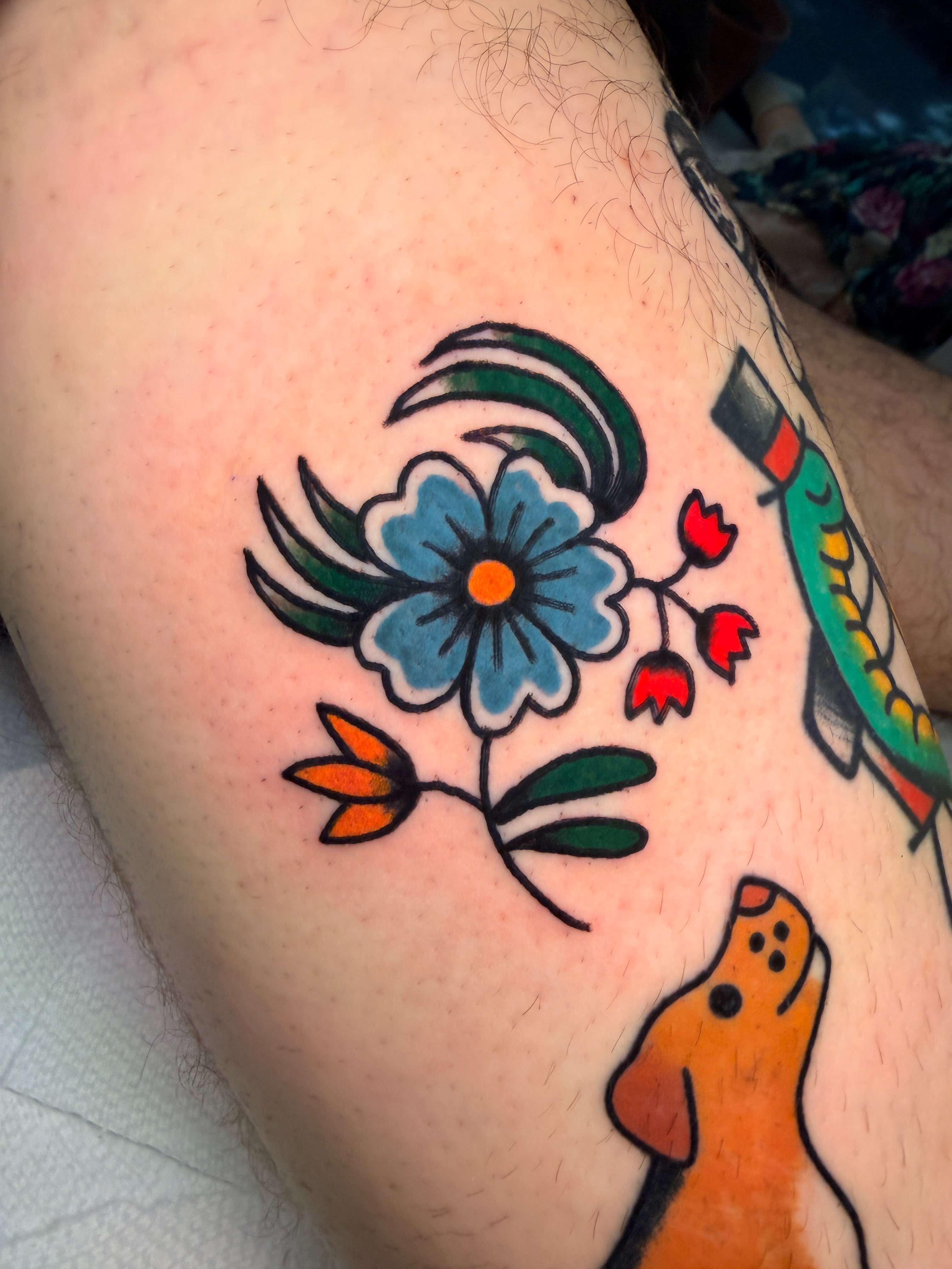 Flower and dog American traditional tattoo on the thigh by Emma Fox Tattoo