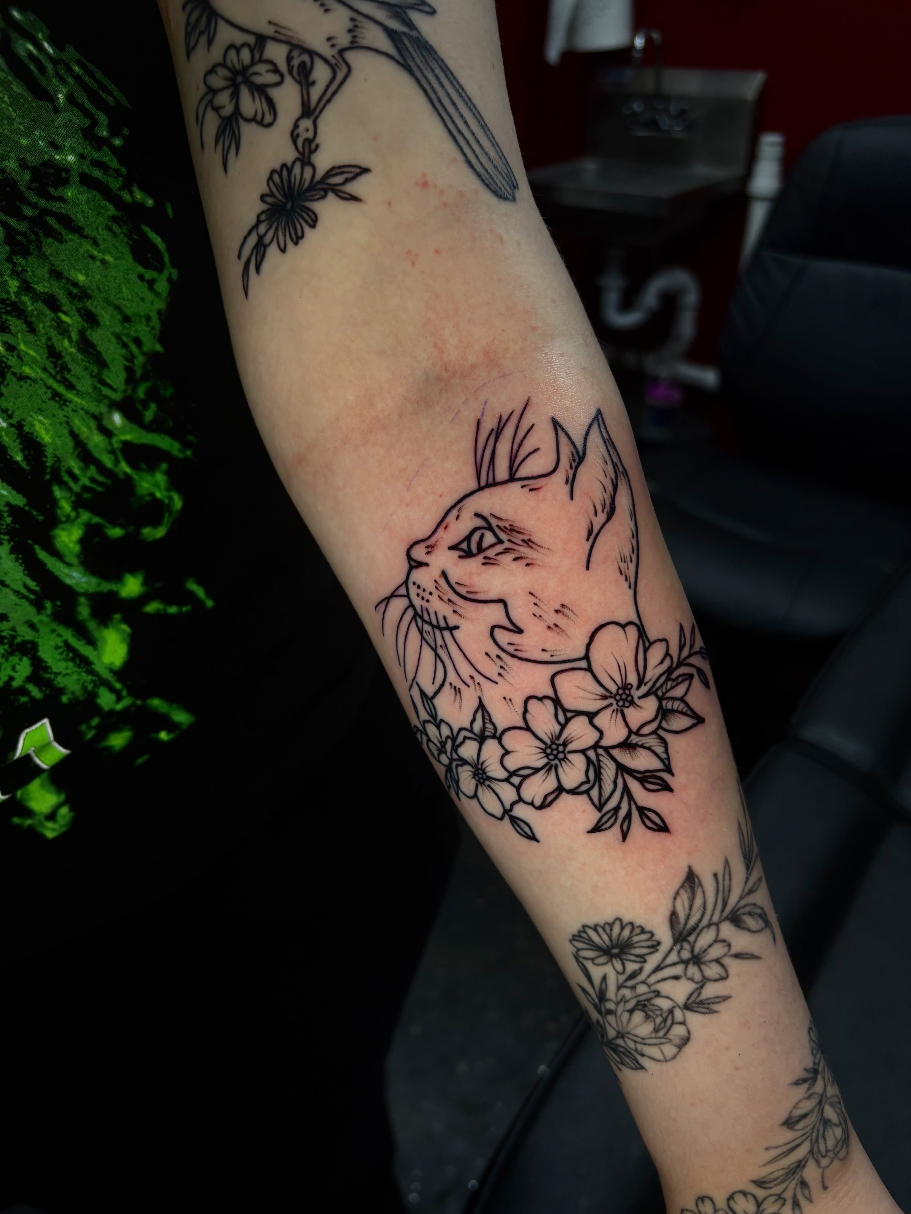 Cat and flowers black and grey tattoo on the forearm by Jenna Clayton