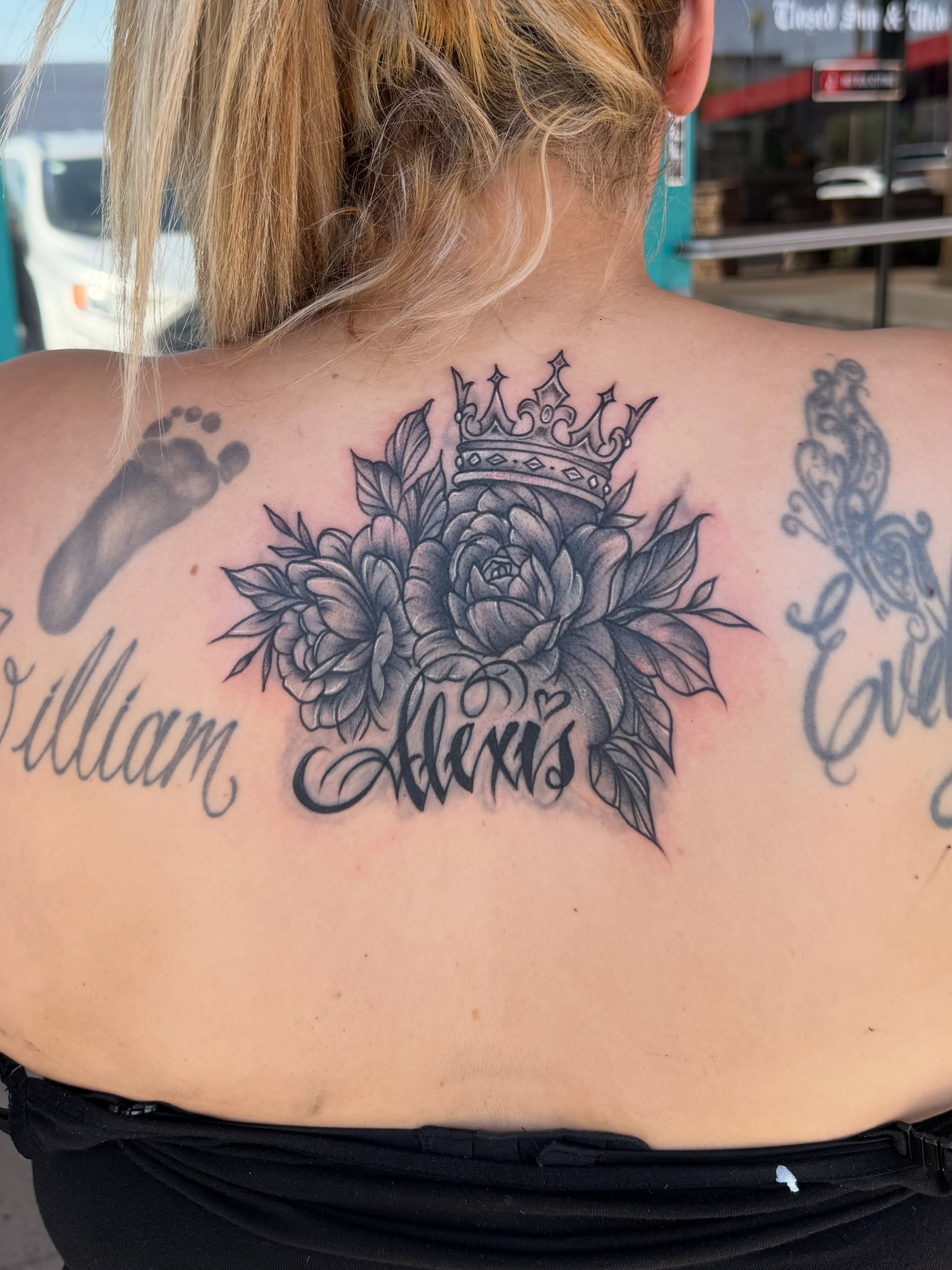 Flowers and crown black and grey tattoo on the back by McKenna Hughes