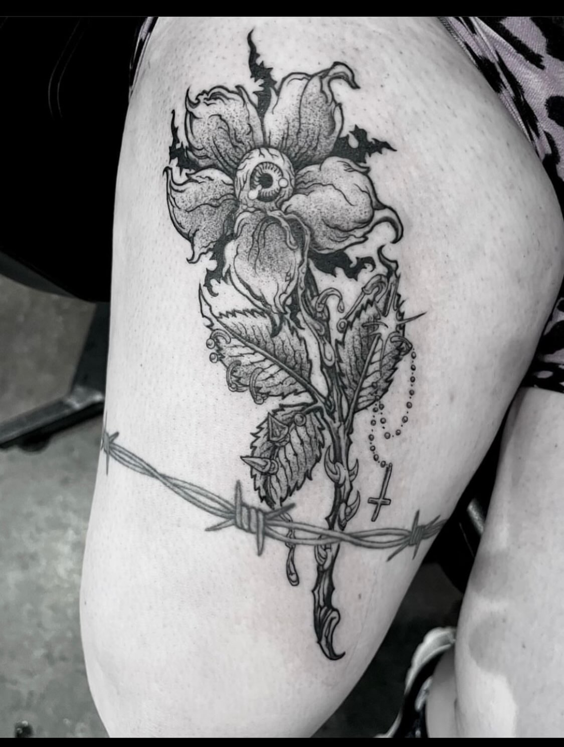 Flower with eye dotwork tattoo on the thigh by Nathan Esteras