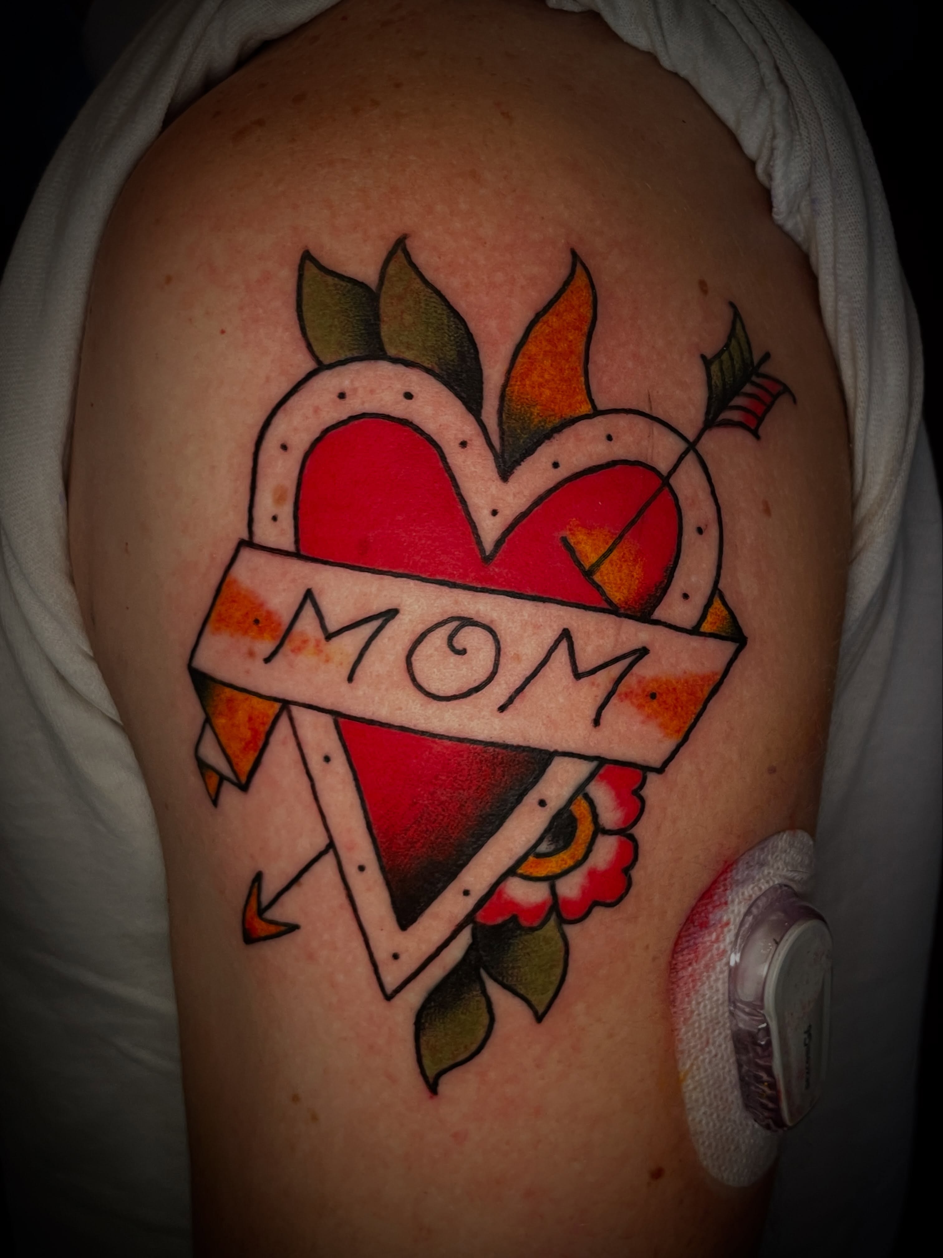 Heart with 'mom' banner American traditional tattoo on the shoulder by Nick Wallin
