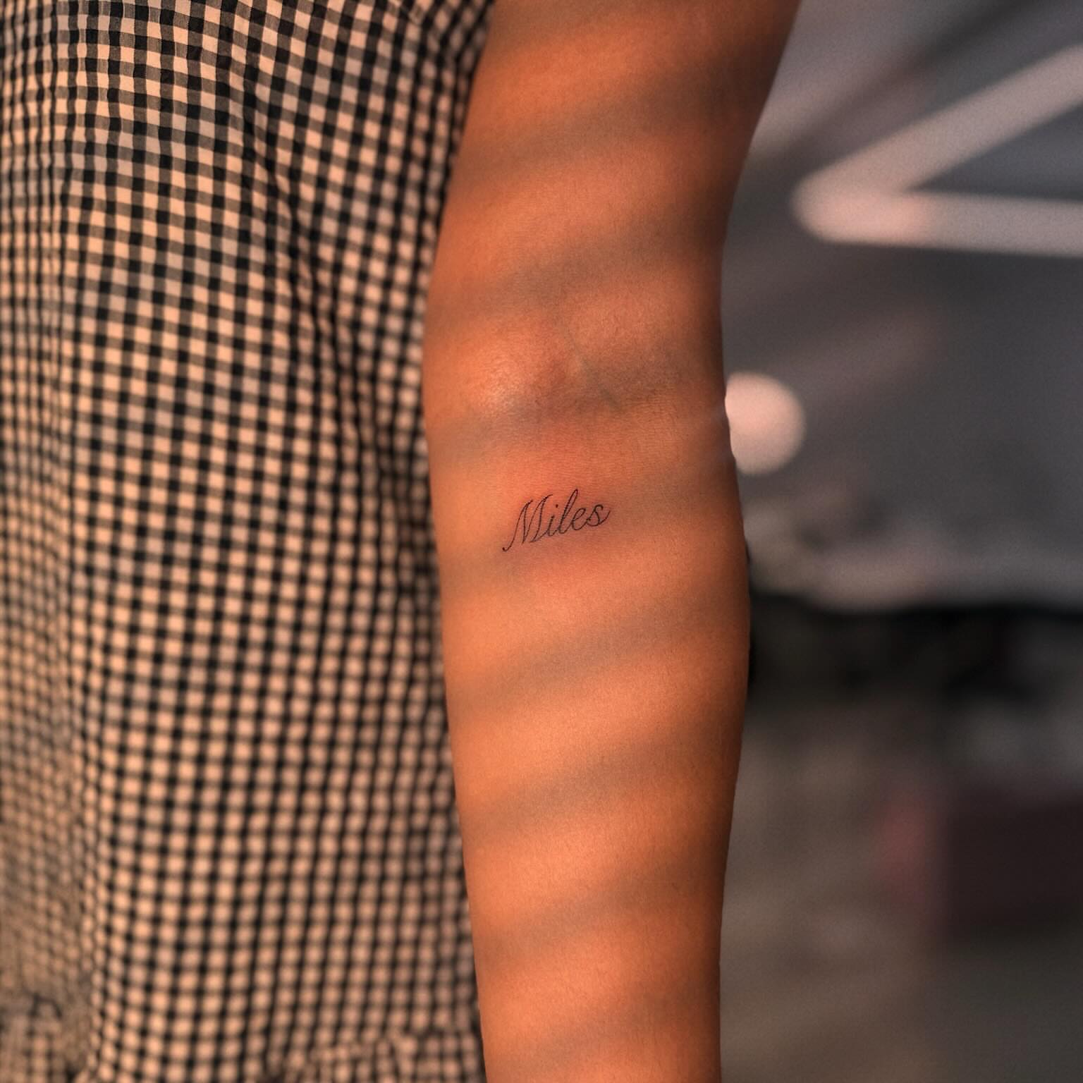 Miles lettering script tattoo on the forearm by Ellie