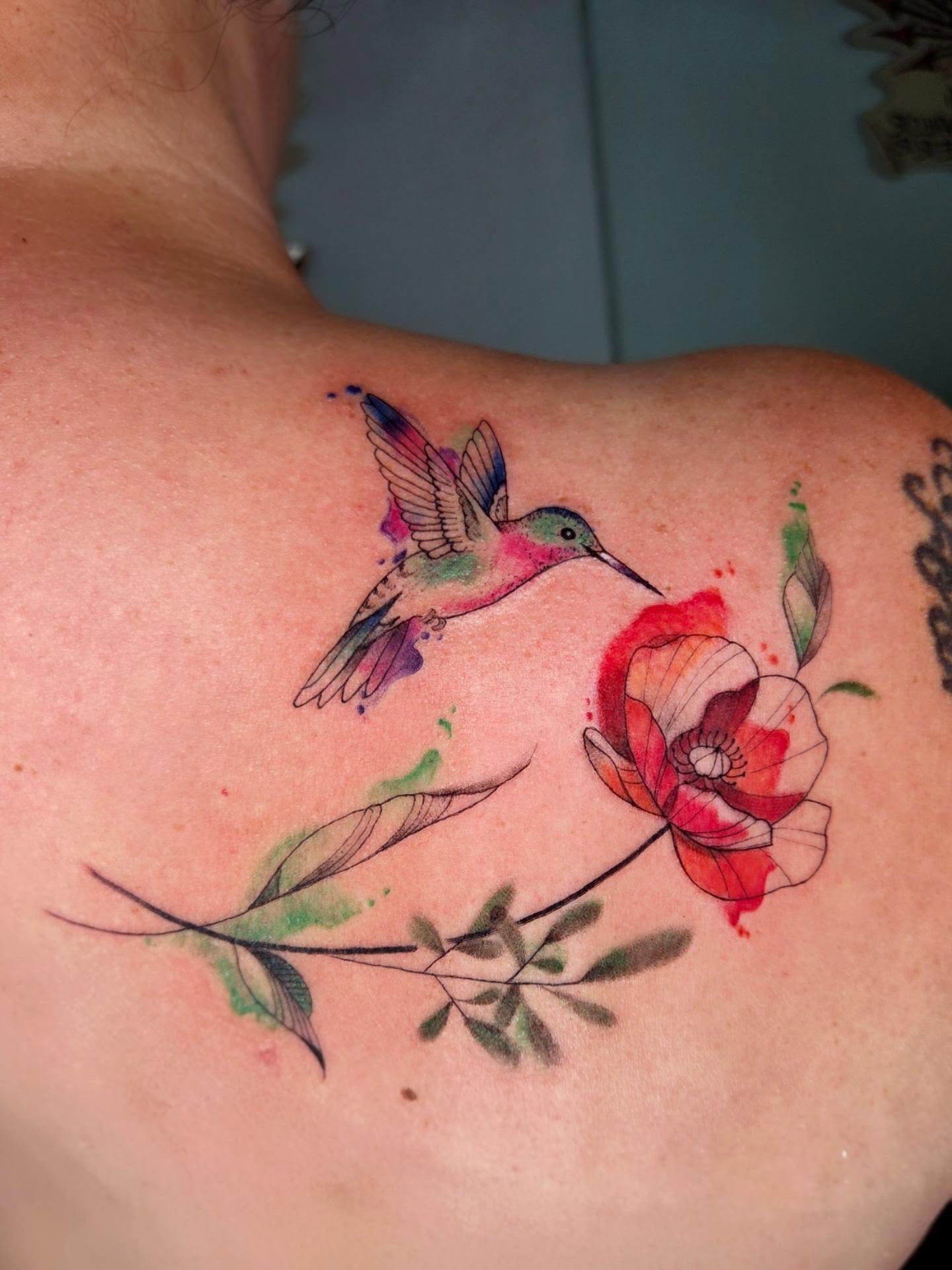 Hummingbird and flower watercolor tattoo on the shoulder by Yvette Cebreros