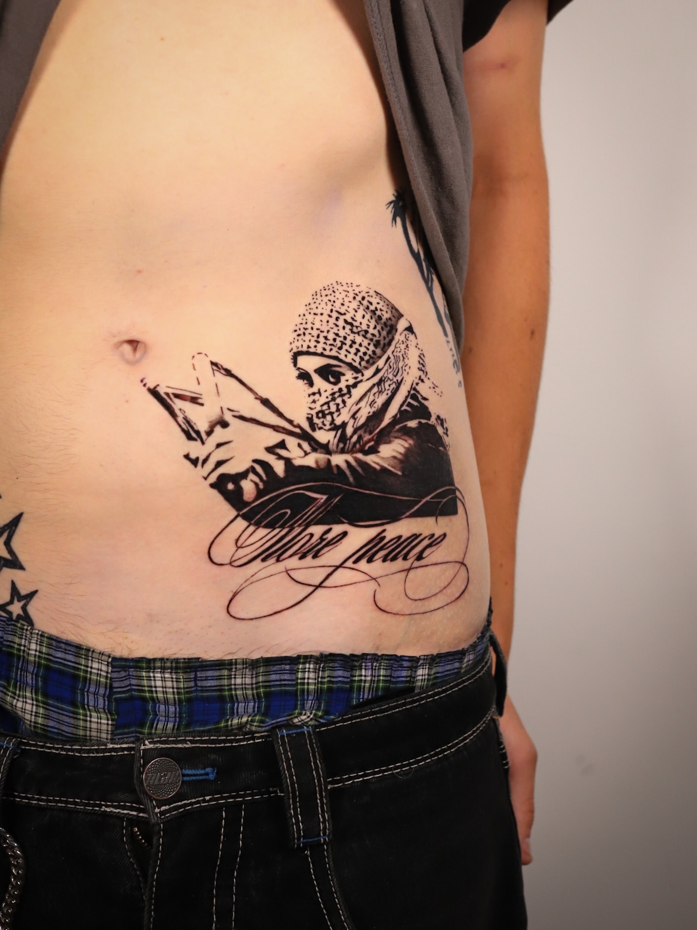Masked figure reading realism tattoo on the ribs by Dani