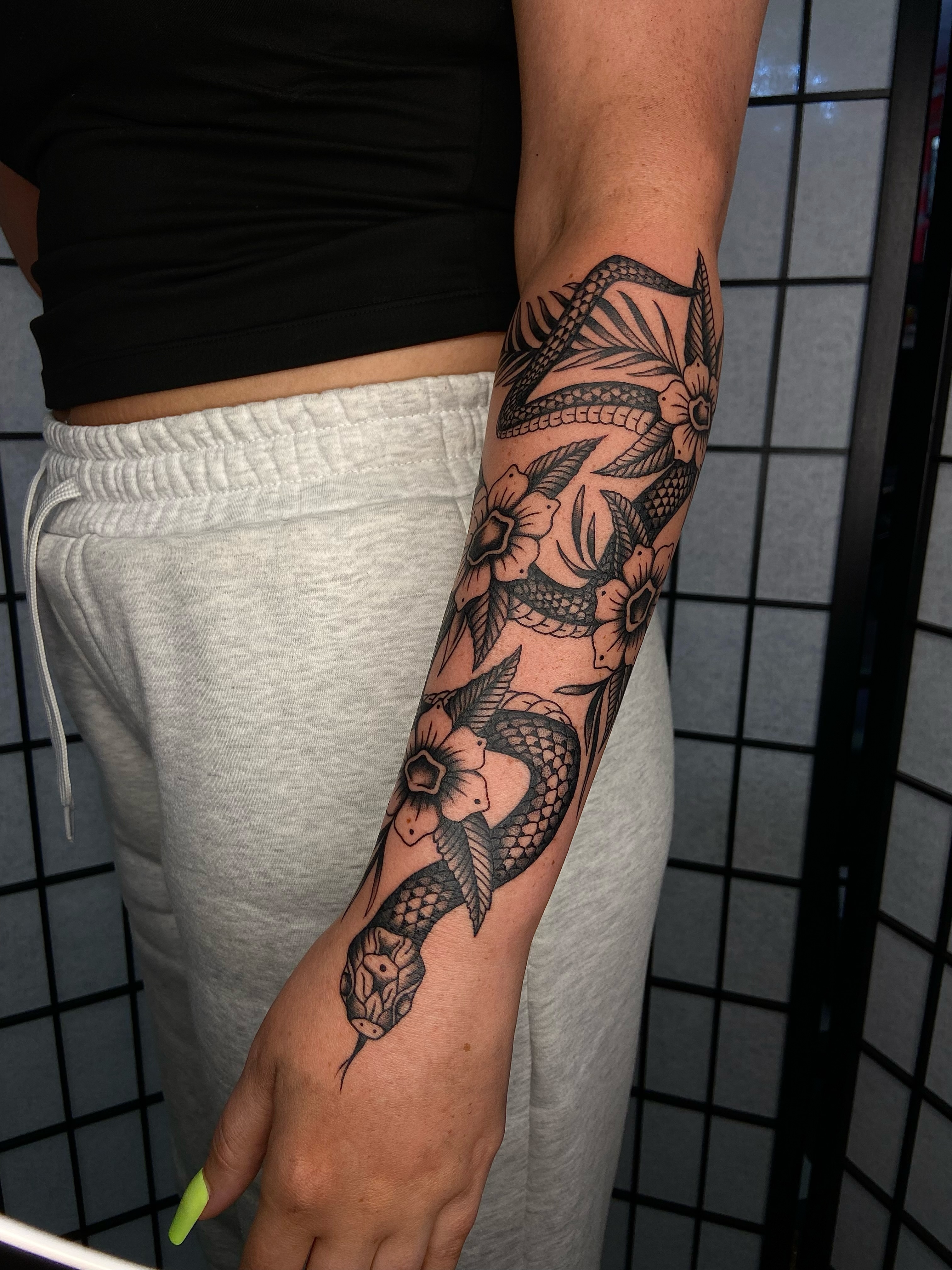 Snake and flowers black and grey tattoo on the forearm by R y a n S m i t h