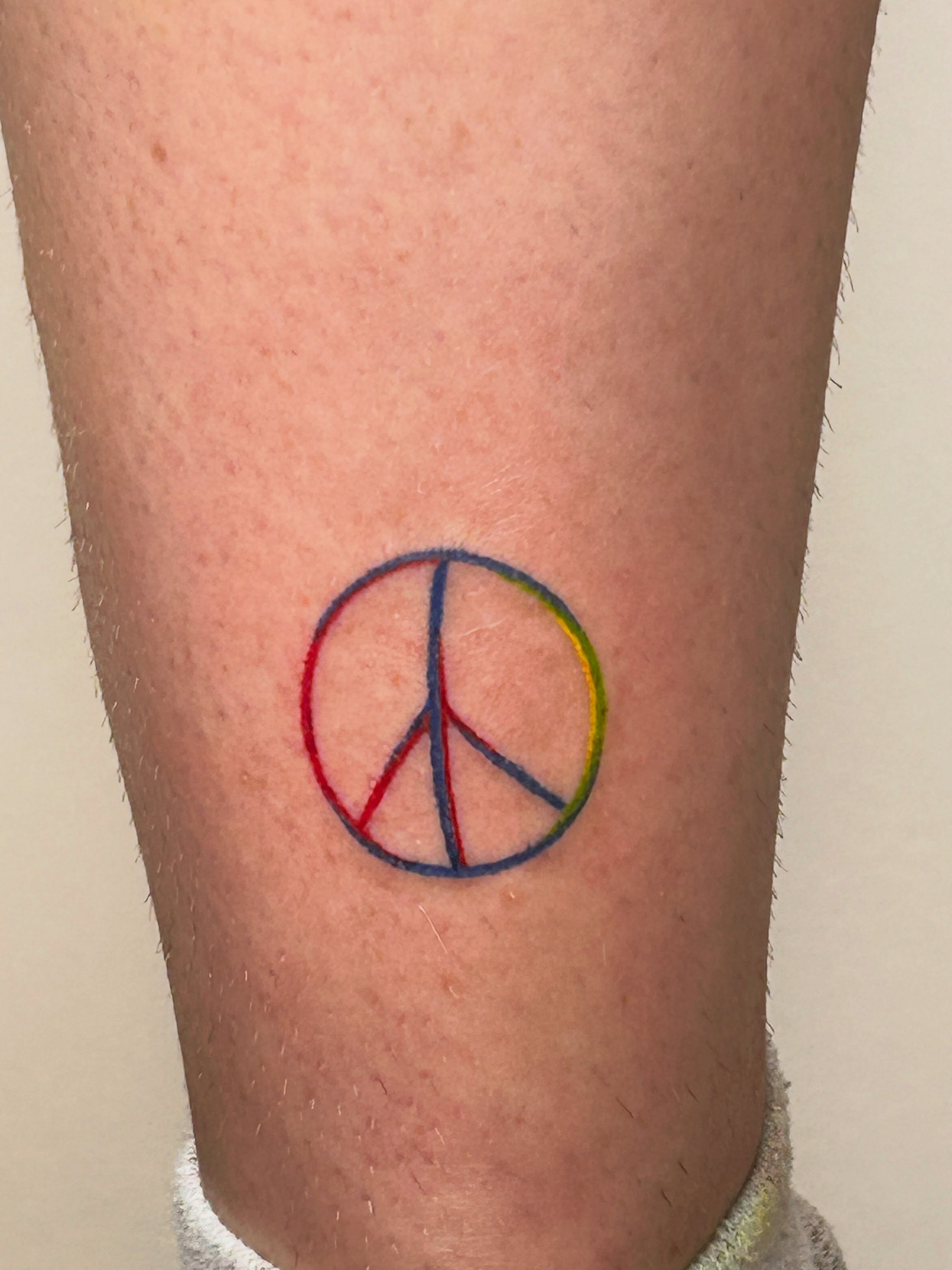 Peace symbol geometric tattoo on the forearm by Nicolette