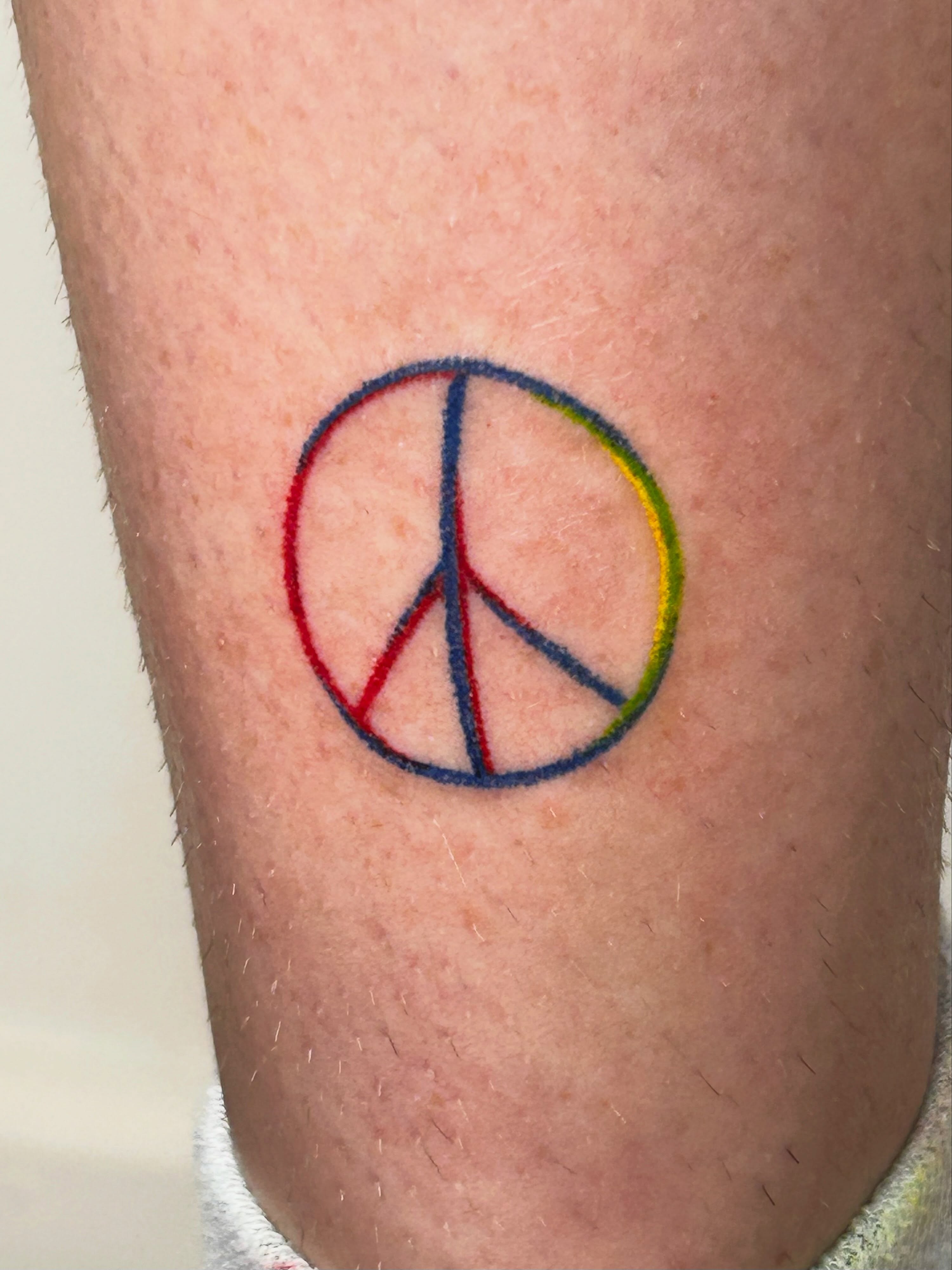 Peace symbol geometric tattoo on the forearm by Nicolette