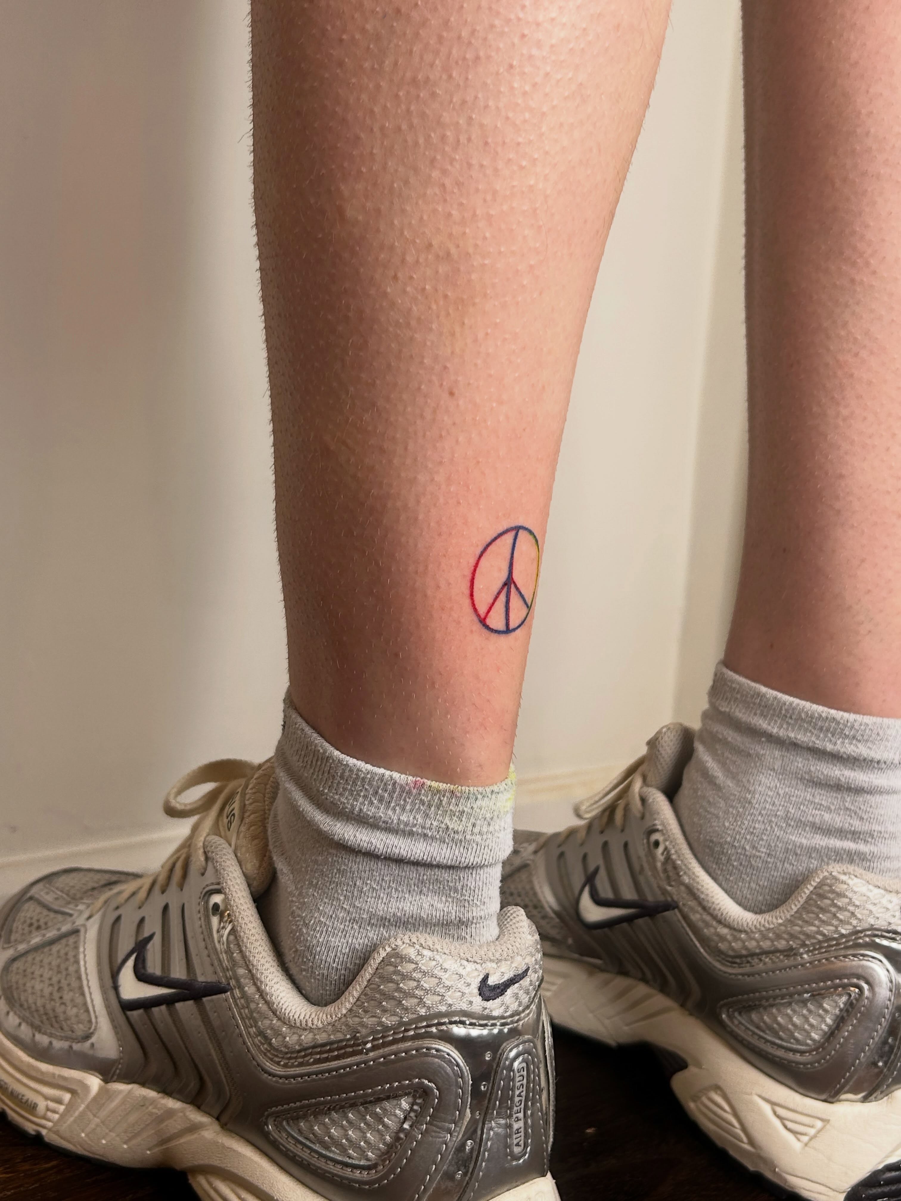 Peace symbol minimalist tattoo on the leg by Nicolette
