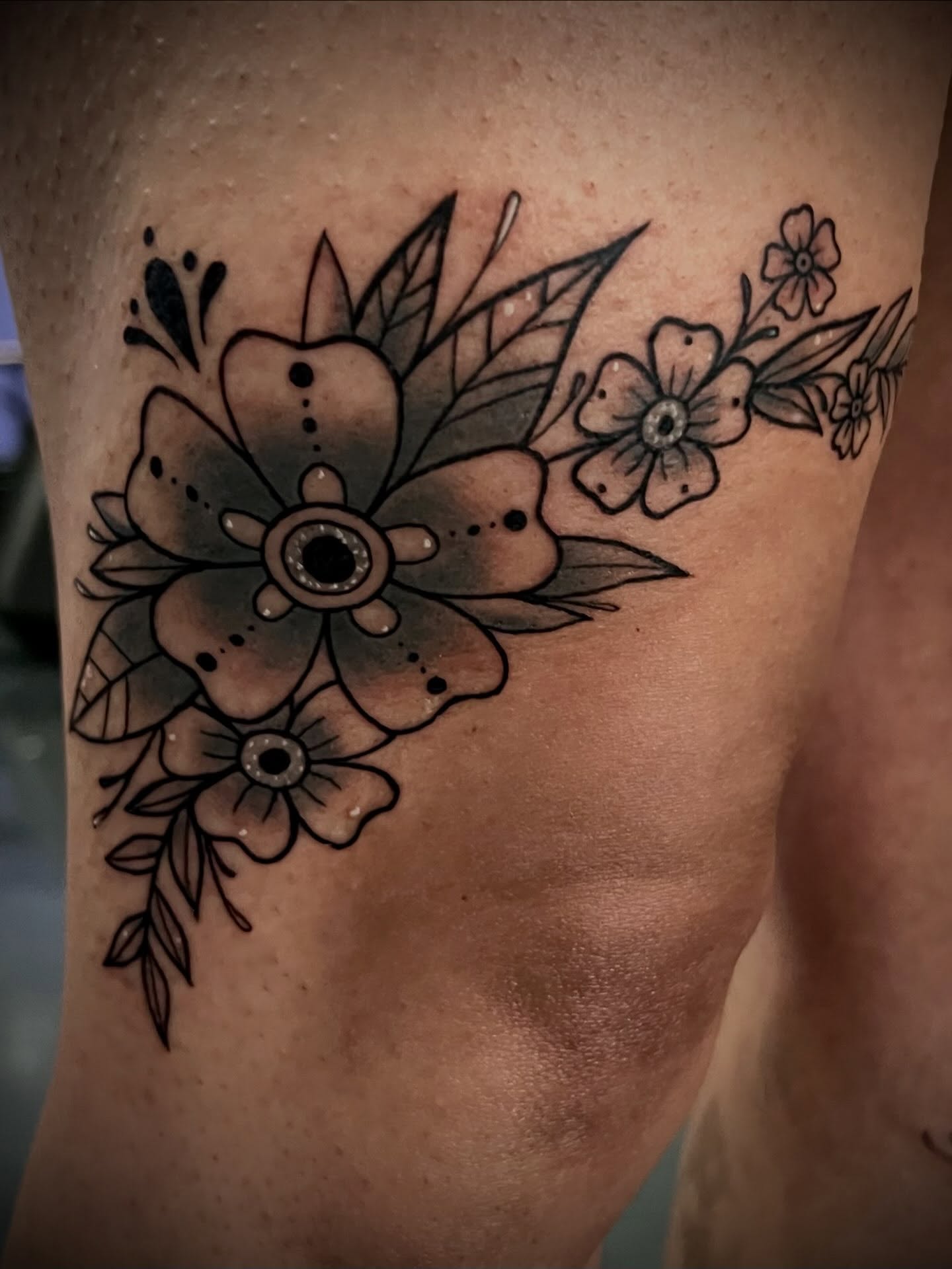 Floral arrangement black and grey tattoo on the thigh by Freya Petersen