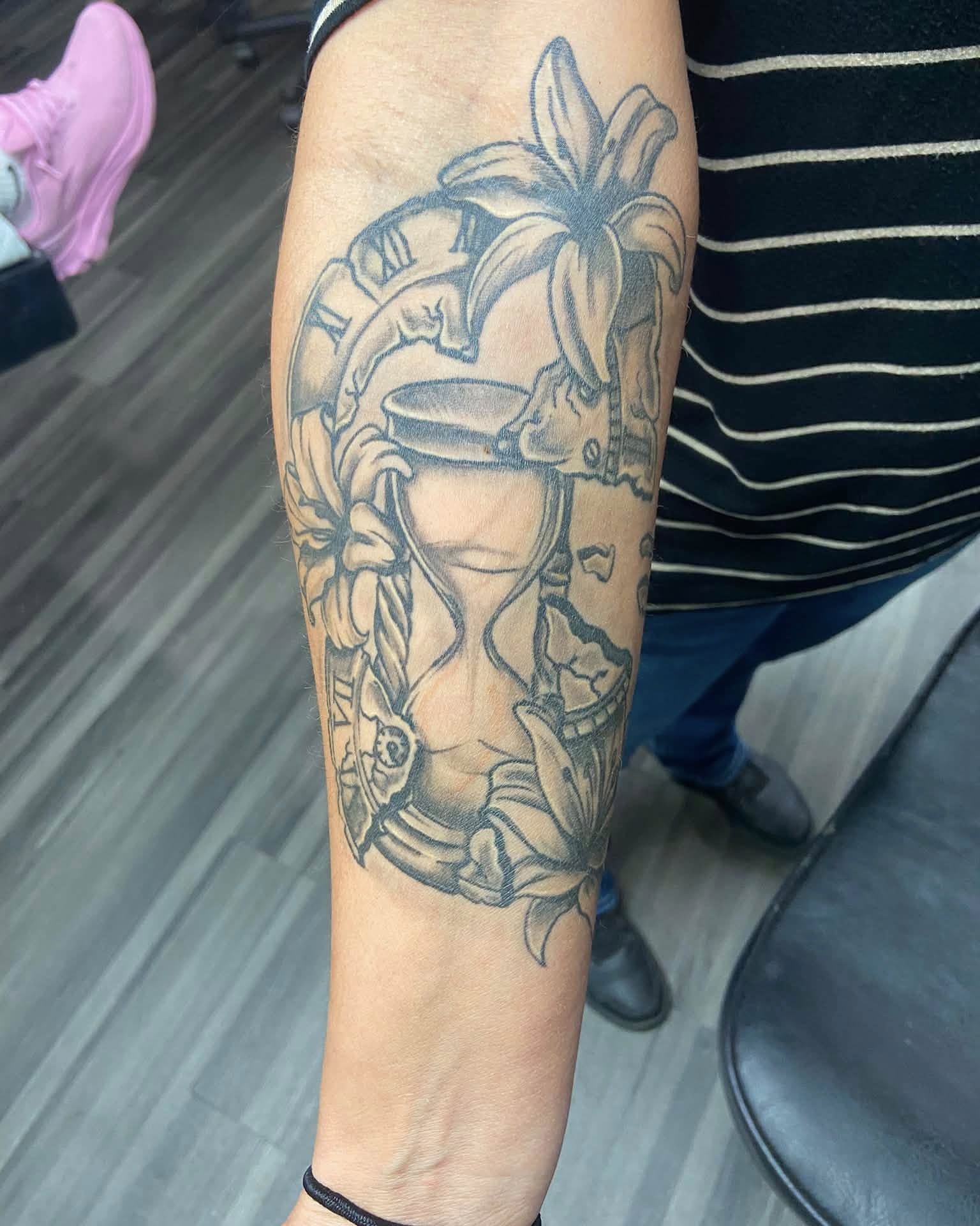 Hourglass and lilies black and grey tattoo on the forearm by Mike Berry