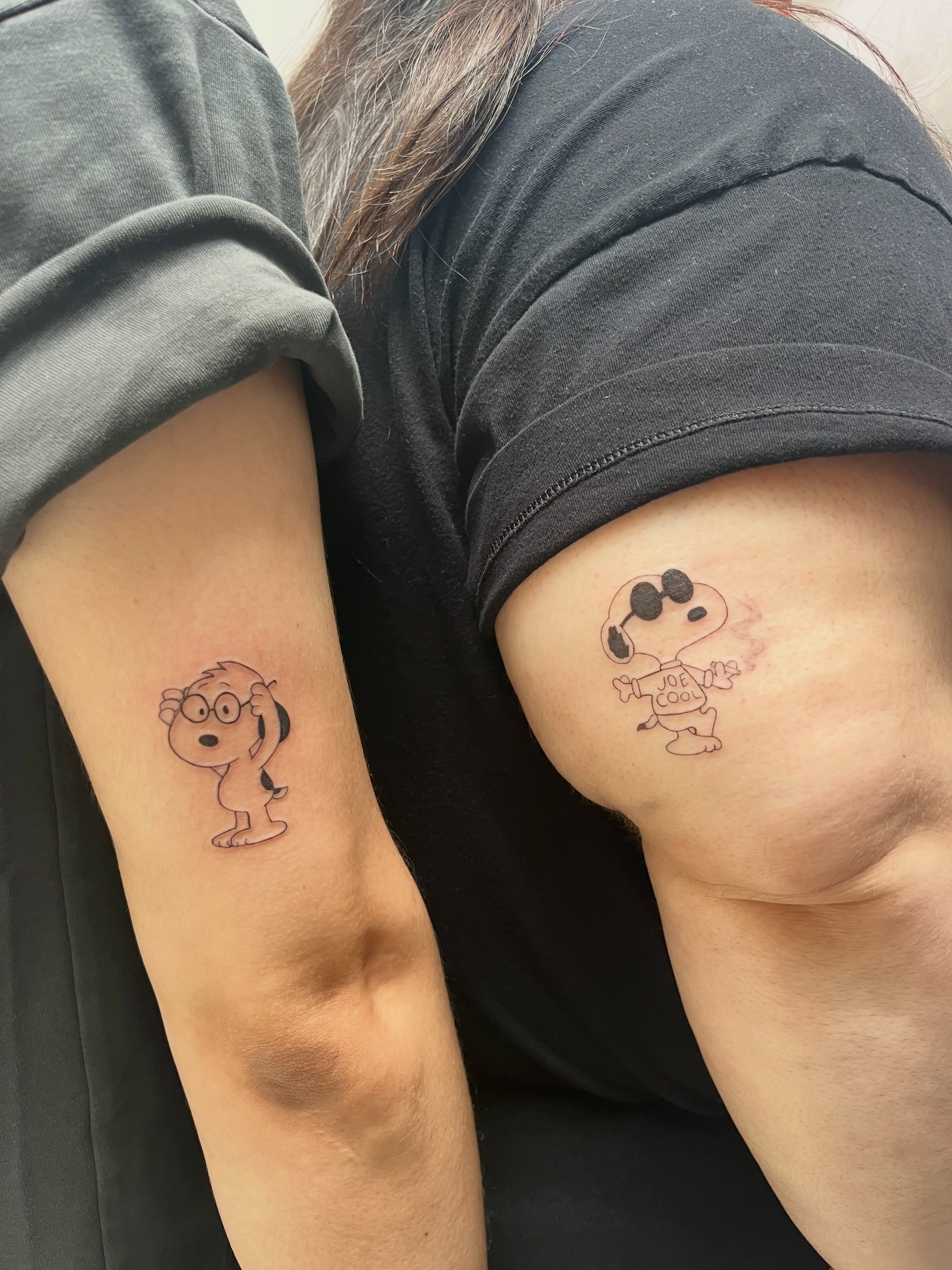 Charlie brown and snoopy black and grey tattoo on the upper arm by Kyra Monterrosa