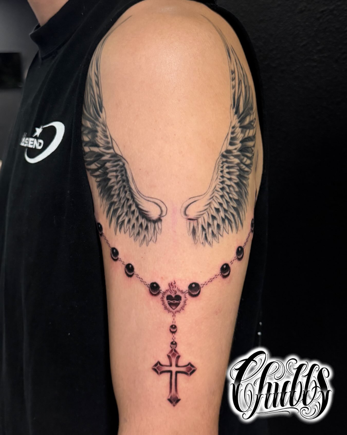 Rosary and cross black and grey tattoo on the forearm by Chubbs