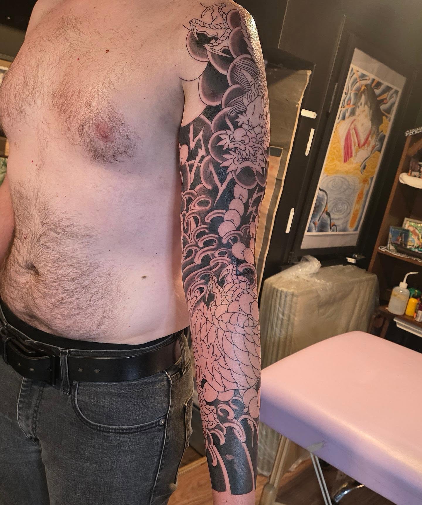Floral and wave pattern black and grey tattoo on the upper arm by Frank Simanton