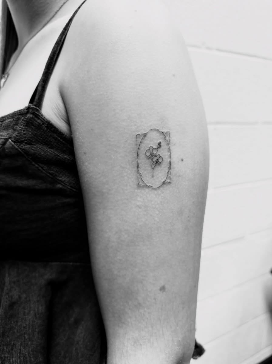 Flower in frame black and grey tattoo on the forearm by Reverie Studio