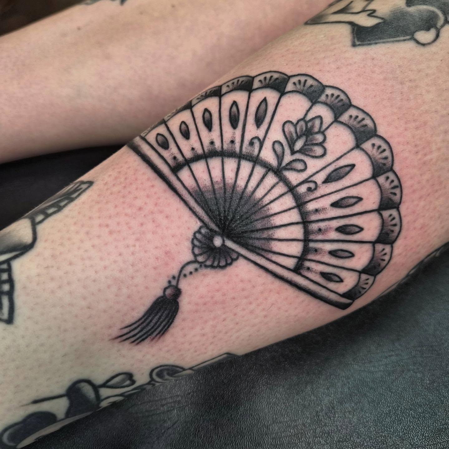 Fan black and grey tattoo on the forearm by Taylor Popkins