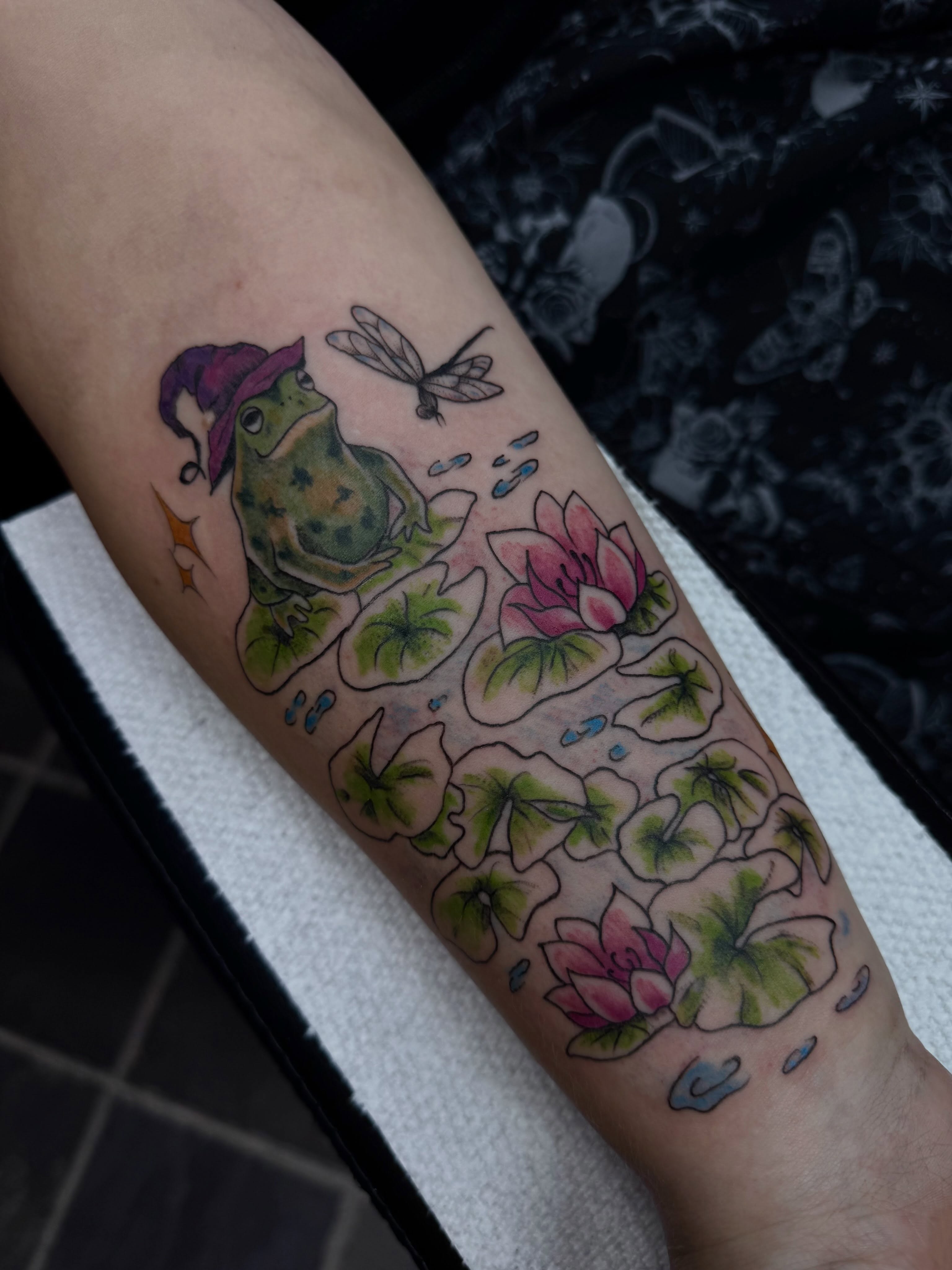 Frog with lily pads new school tattoo on the forearm by olivia reed