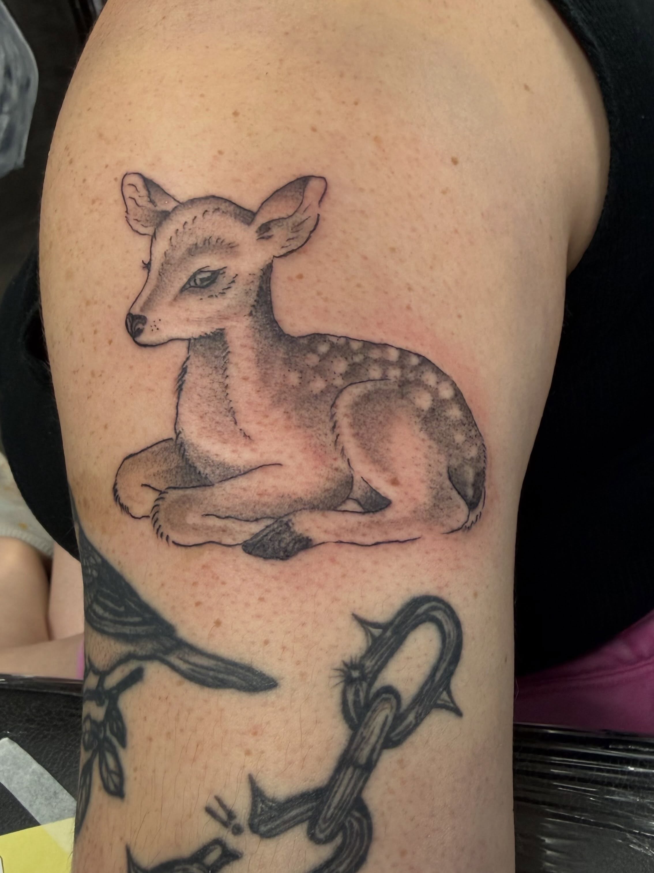 Deer black and grey tattoo on the upper arm by Daniel Smith