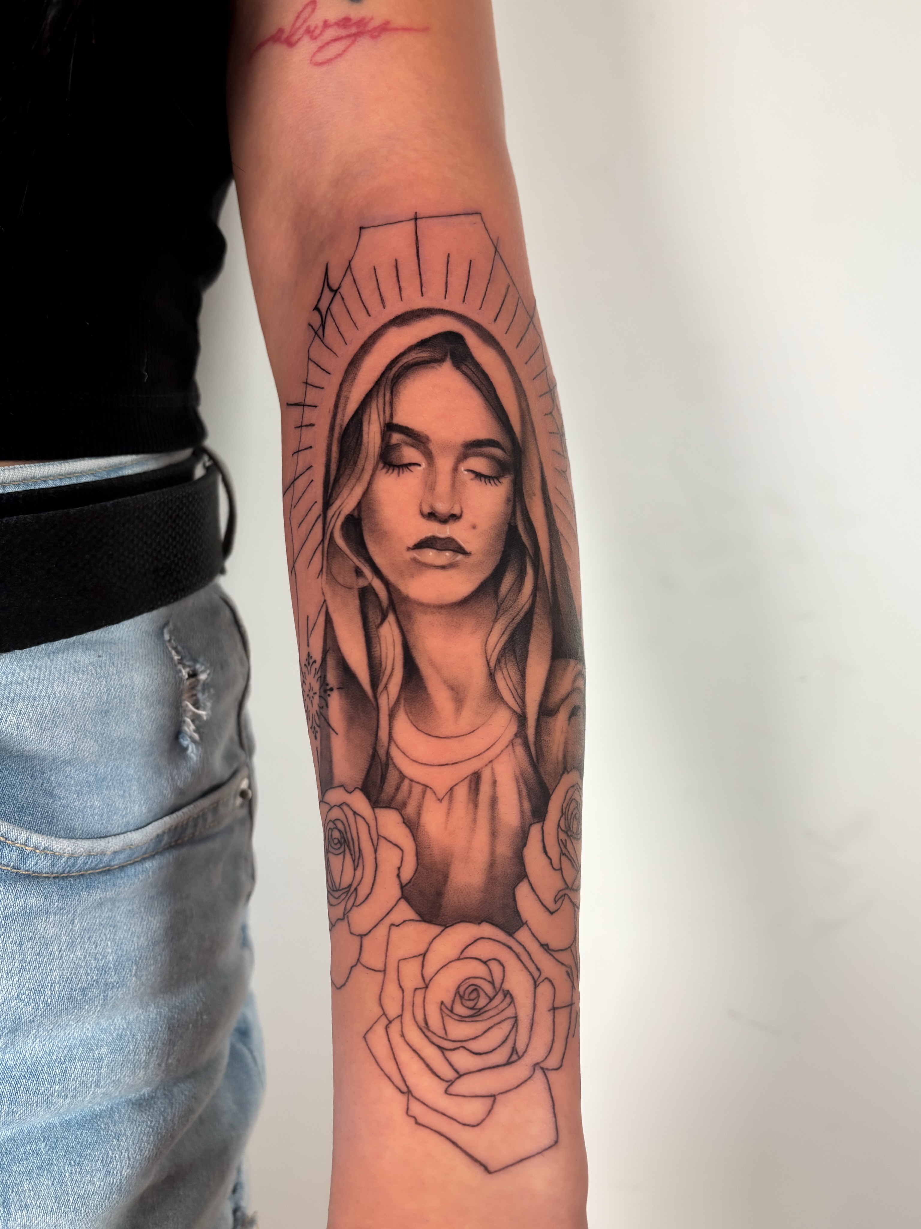 Religious figure with roses black and grey tattoo on the forearm by Dani