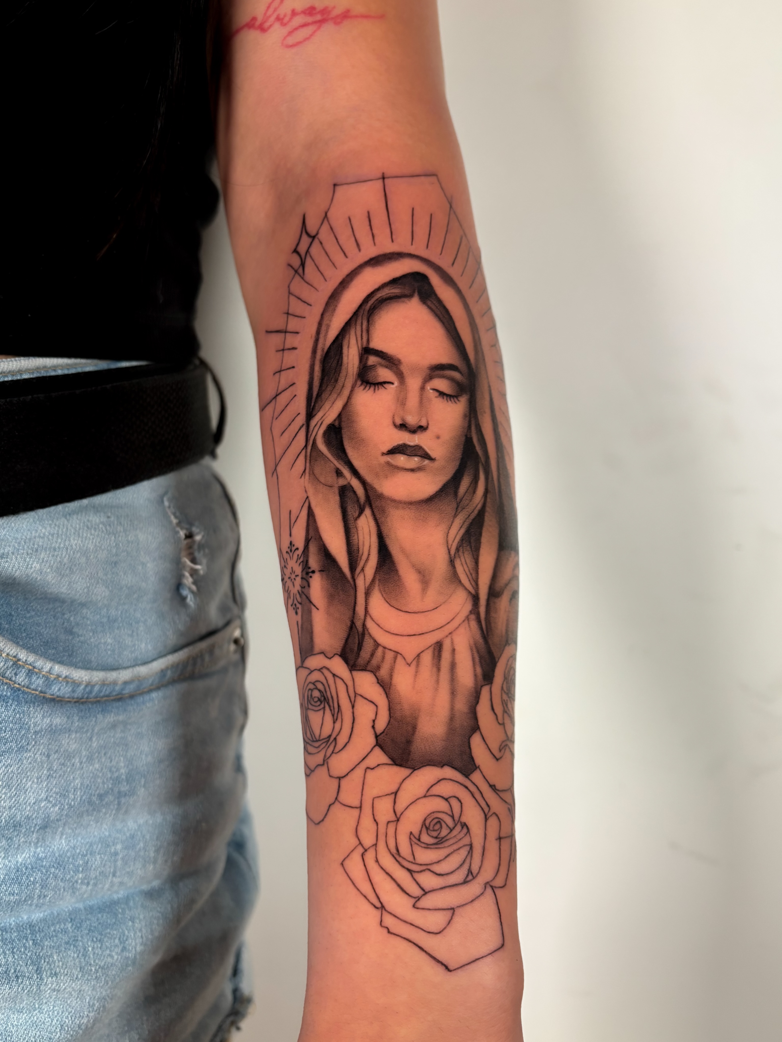 Religious figure with roses black and grey tattoo on the forearm by Dani