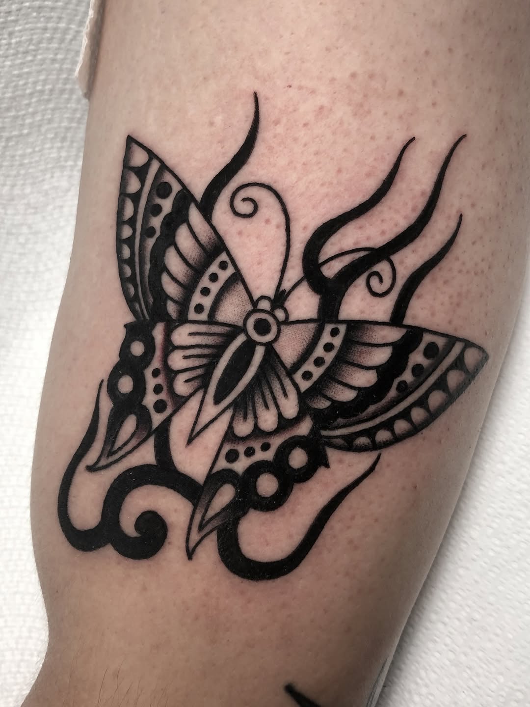 Moth with flames tribal tattoo on the forearm by Angel West