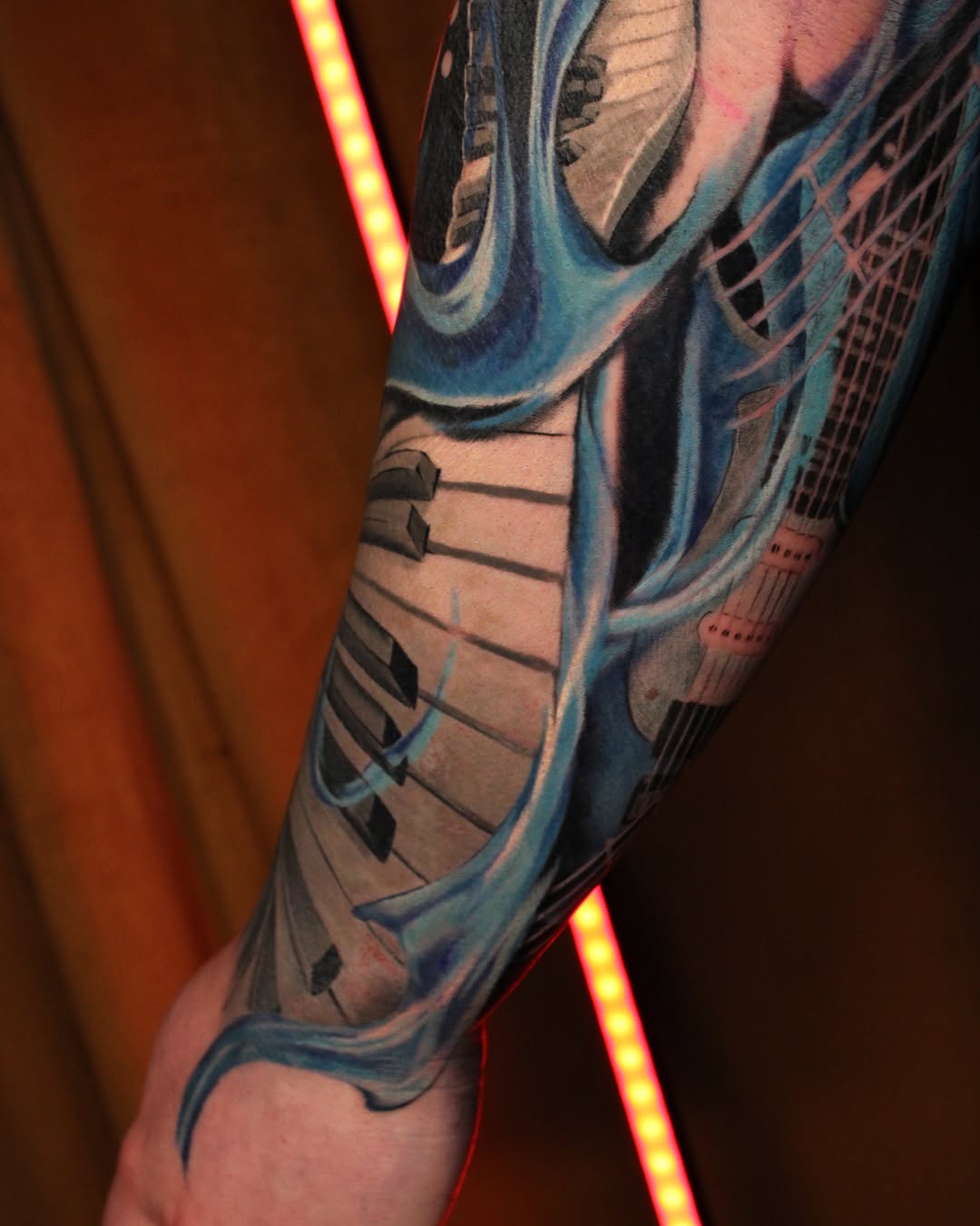 Keyboard and guitar realism tattoo on the forearm by Eva Williams