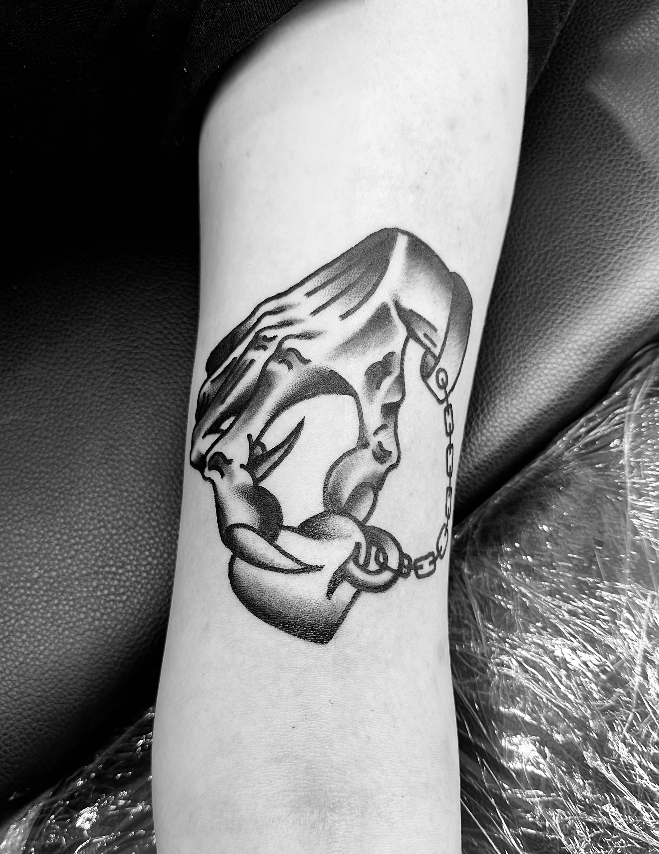 Skull with chains black and grey tattoo on the forearm by Jimmy Kelley