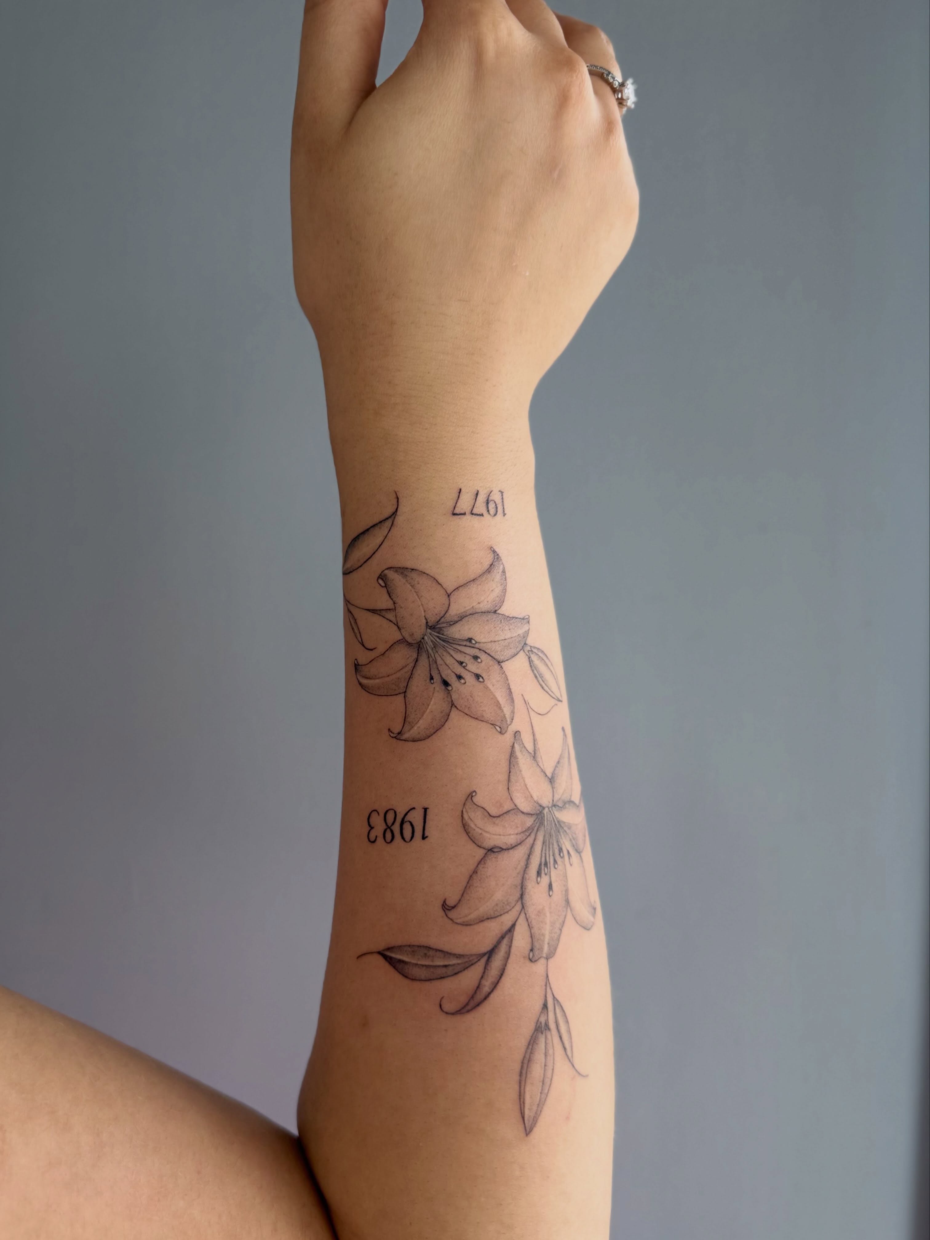 Lilies black and grey tattoo on the forearm by Silva Wellen