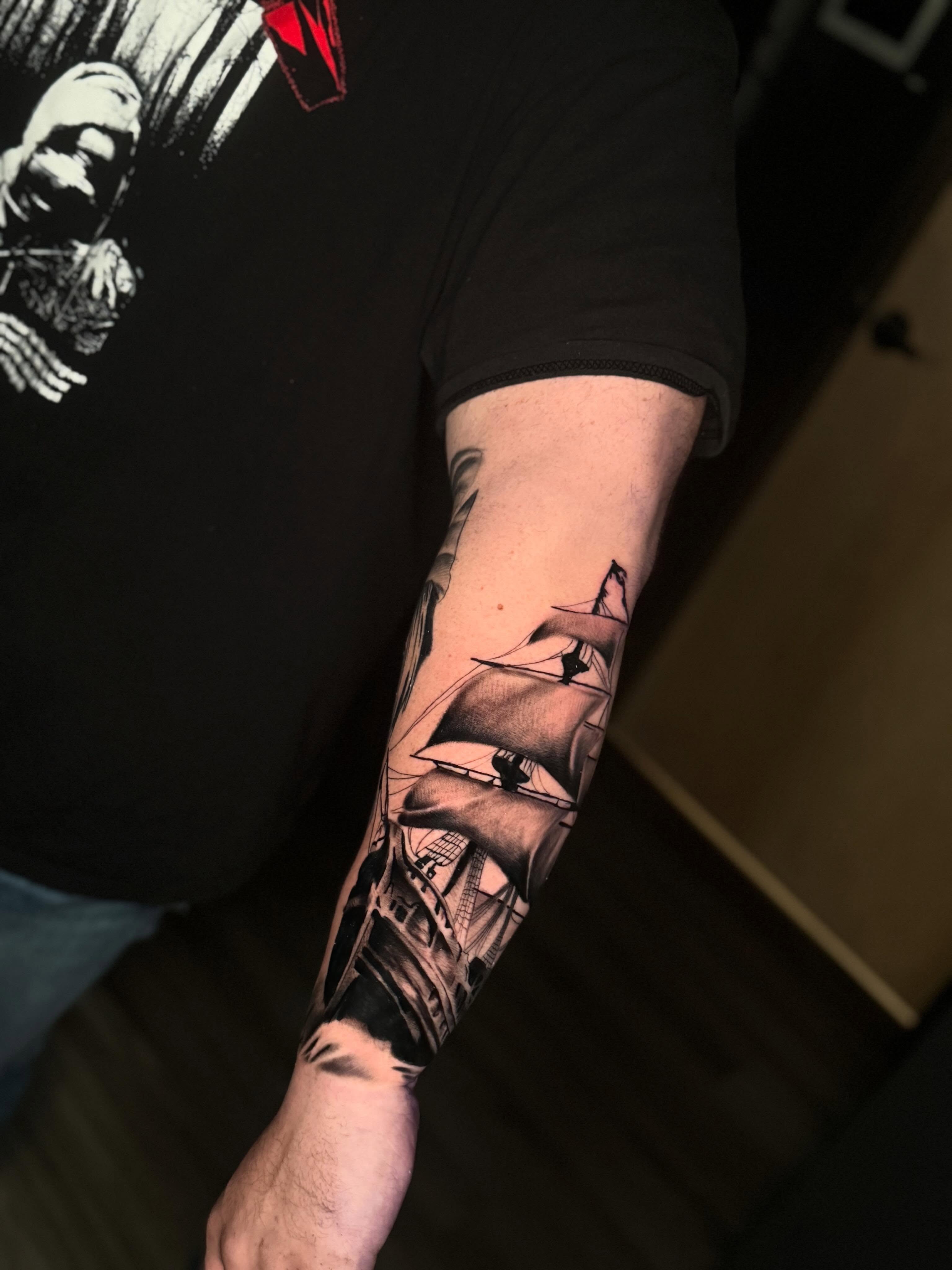 Ship and cityscape realism tattoo on the forearm by Adrián Banuelos