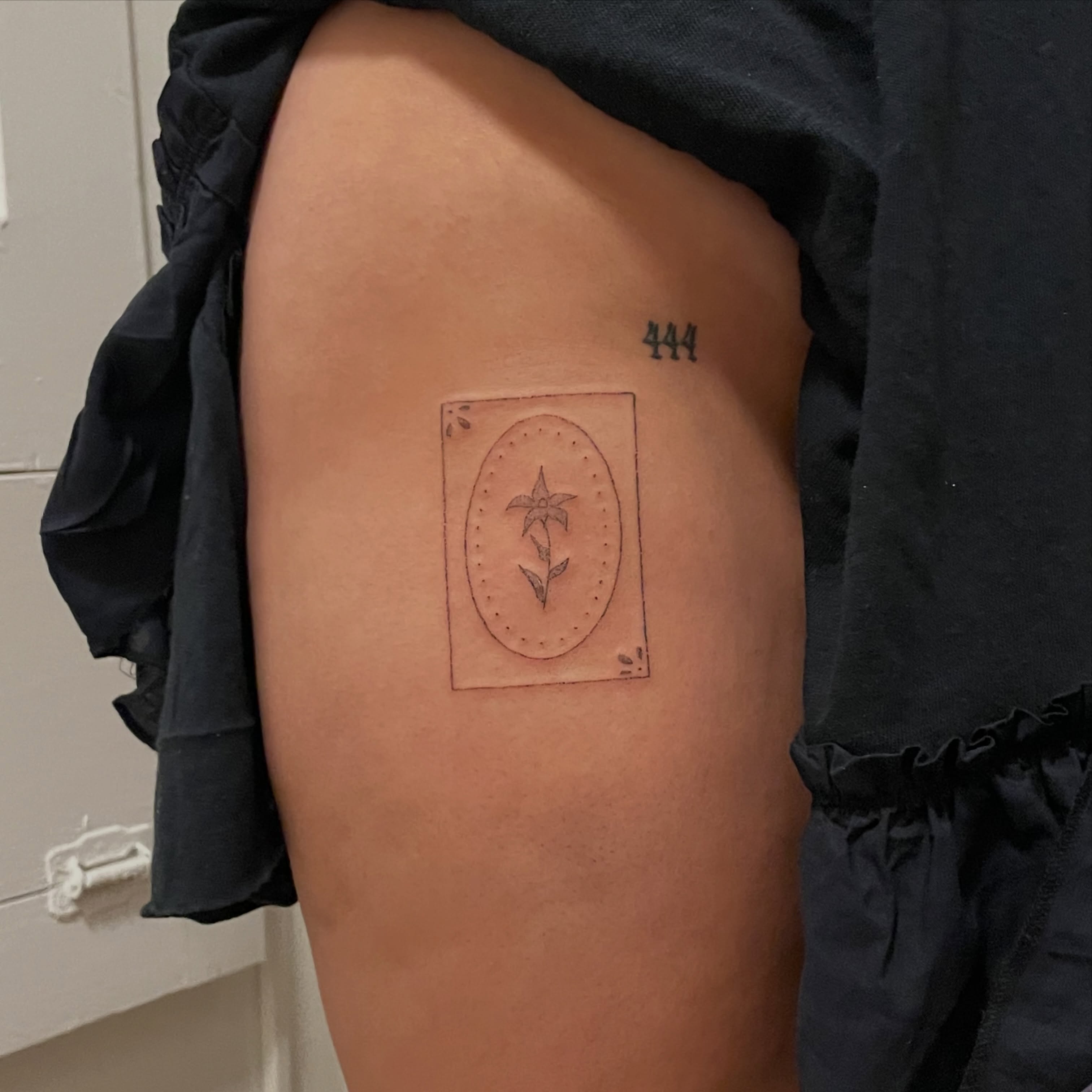 Flower in oval dotwork tattoo on the thigh by Alyssa