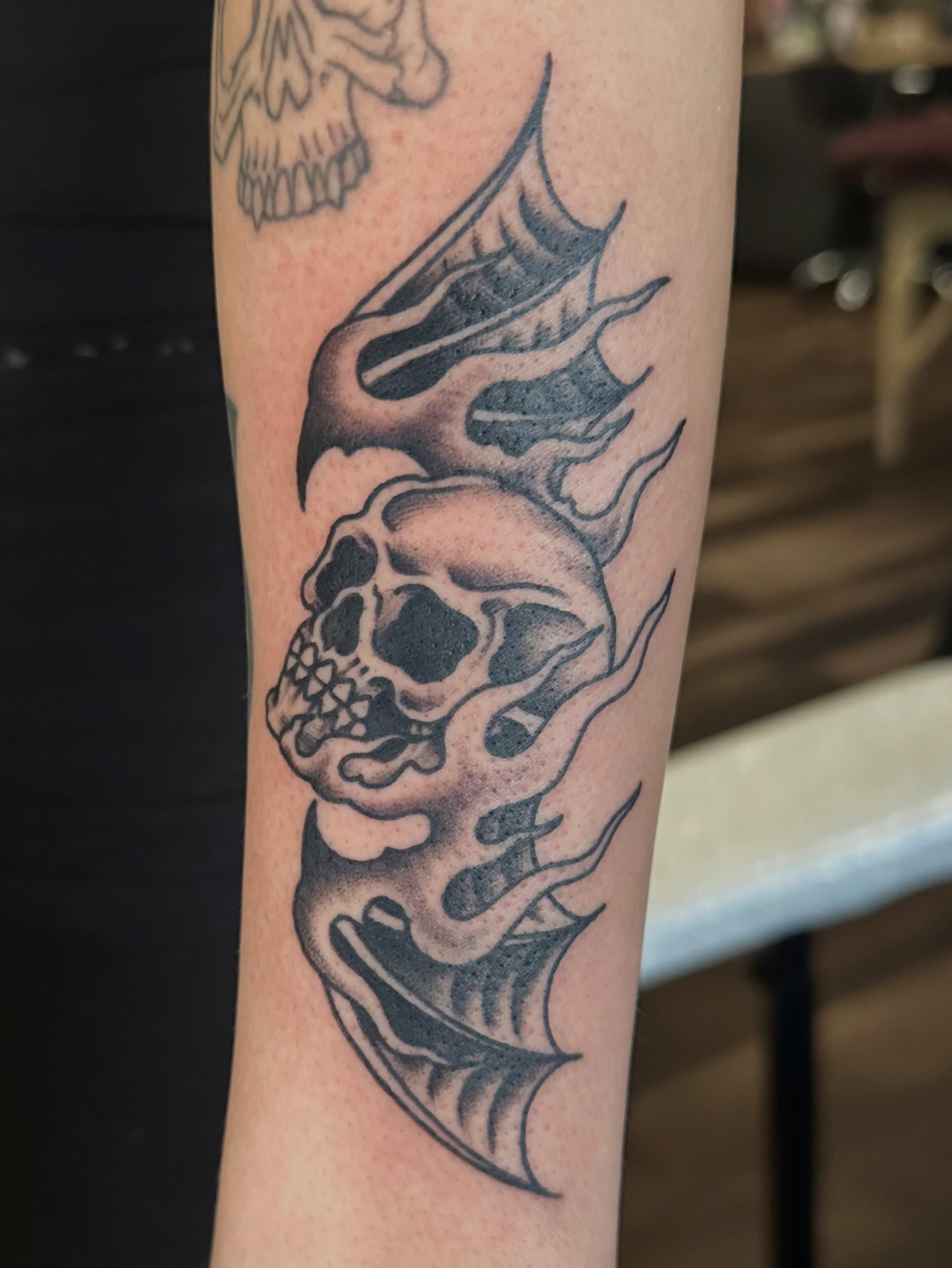 Flaming skull black and grey tattoo on the forearm by Lauren Howard Tattoos