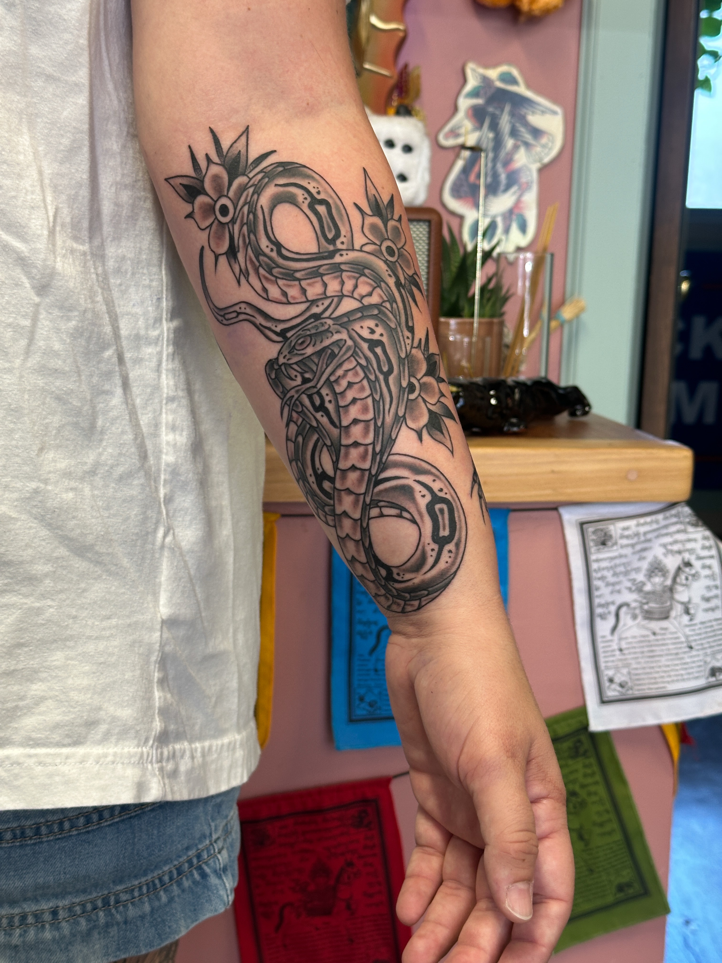 Snake and flowers American traditional tattoo on the forearm by Tattooing by Patty Valentine