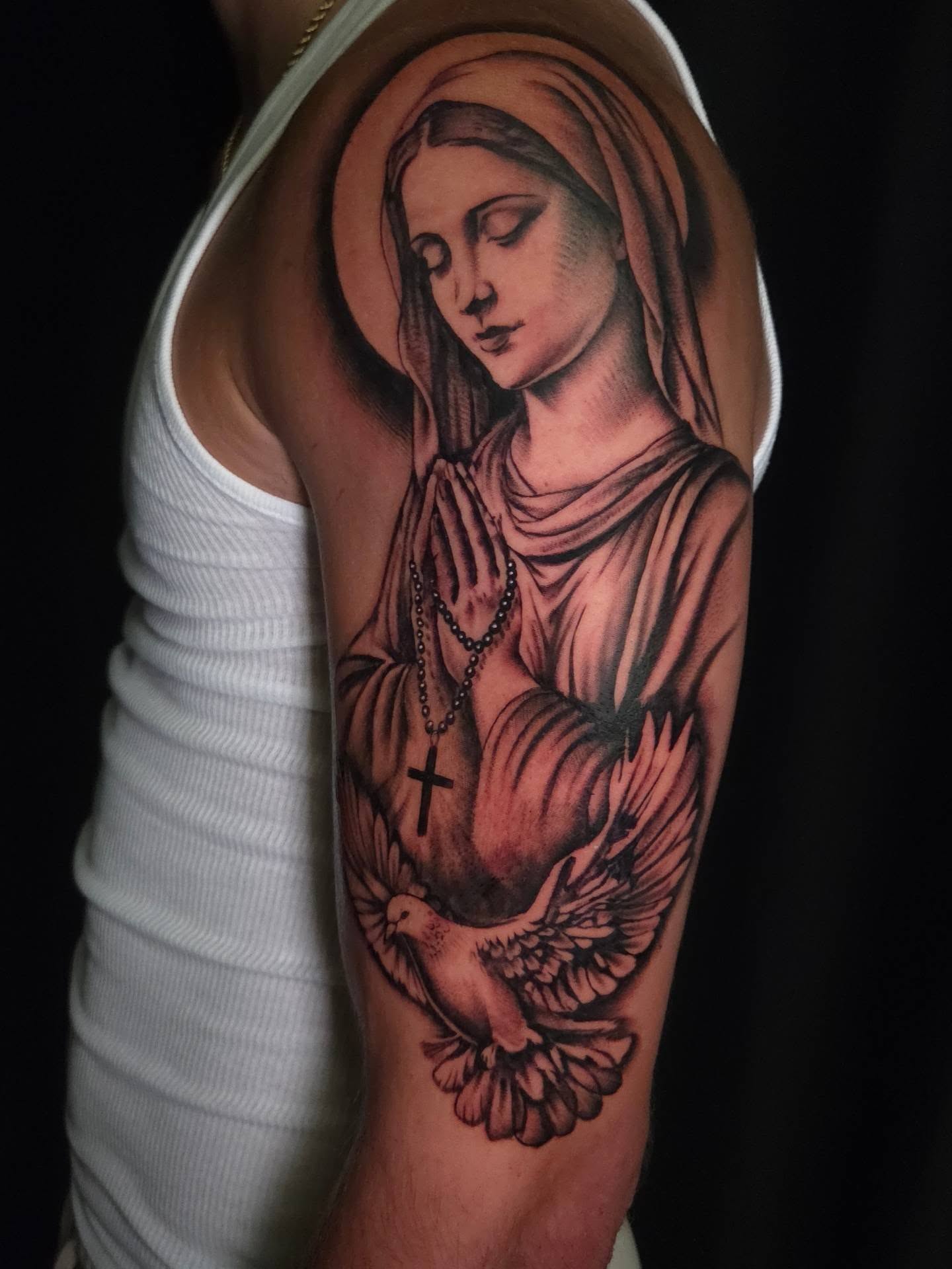 Religious figure praying realism tattoo on the upper arm by Maya Neideck