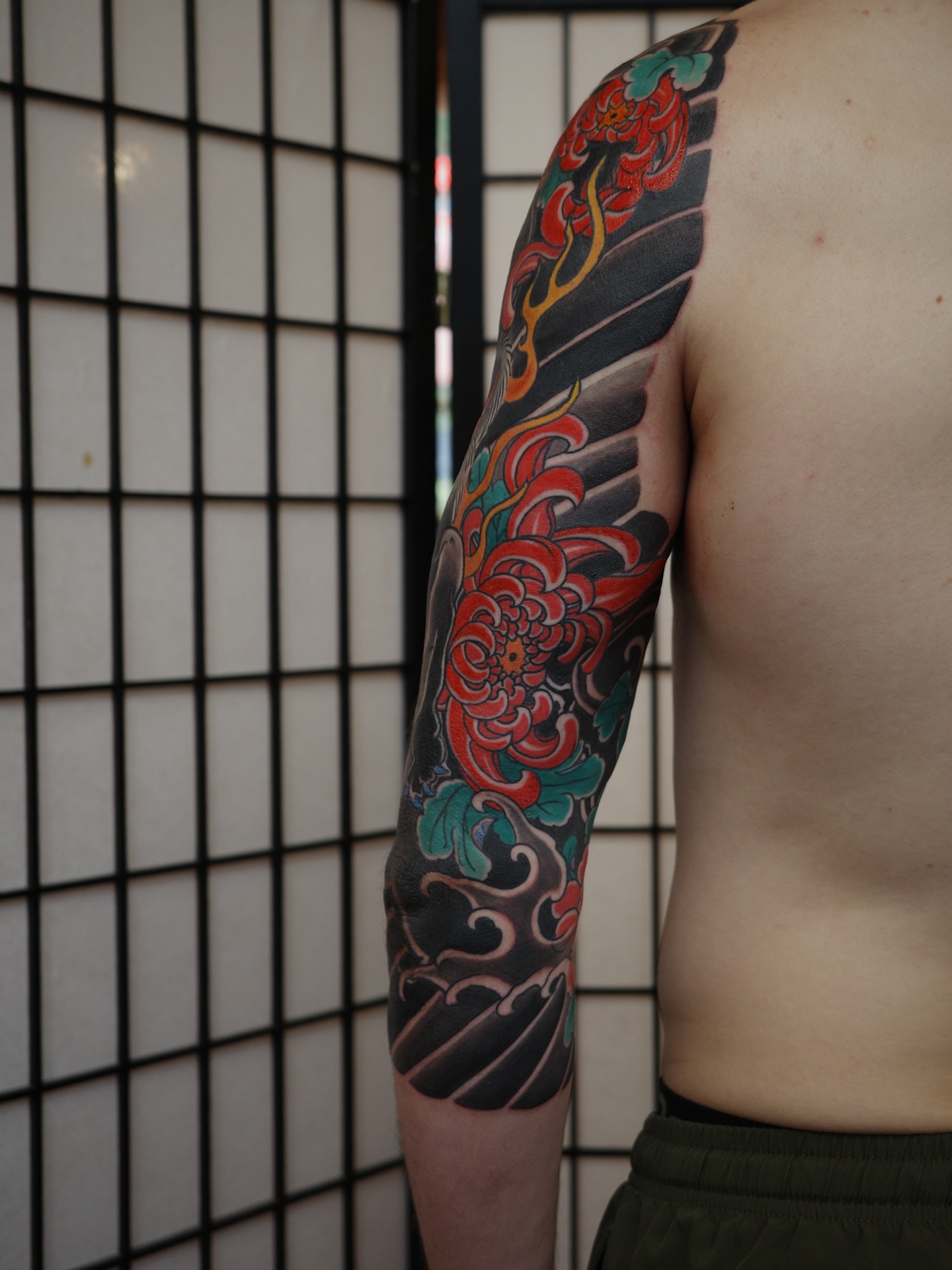Chrysanthemum and flames japanese irezumi tattoo on the upper arm by Innokenty Meshchakov, Portland, Oregon