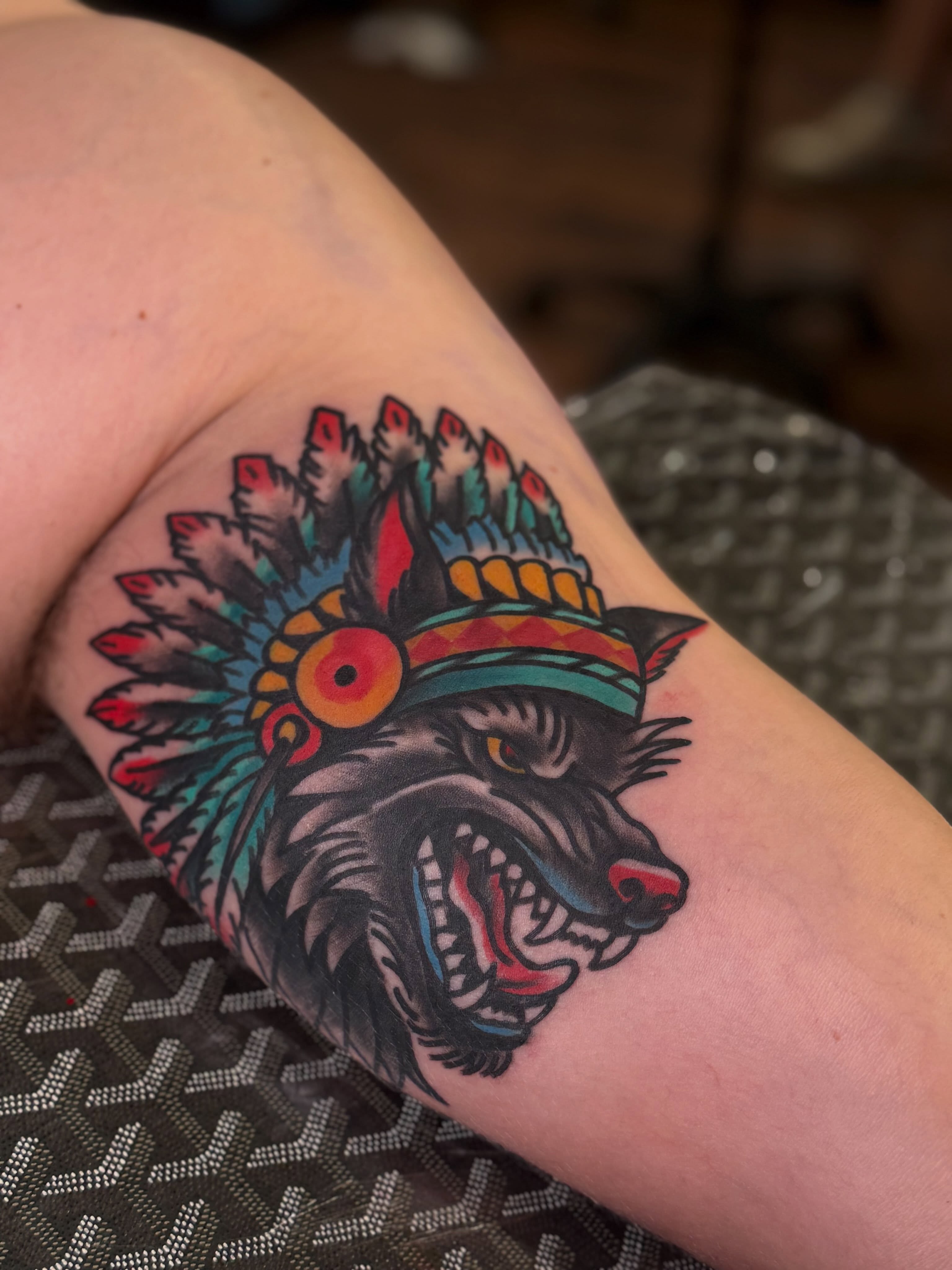 Wolf with headdress American traditional tattoo on the thigh by Robbie Roberson