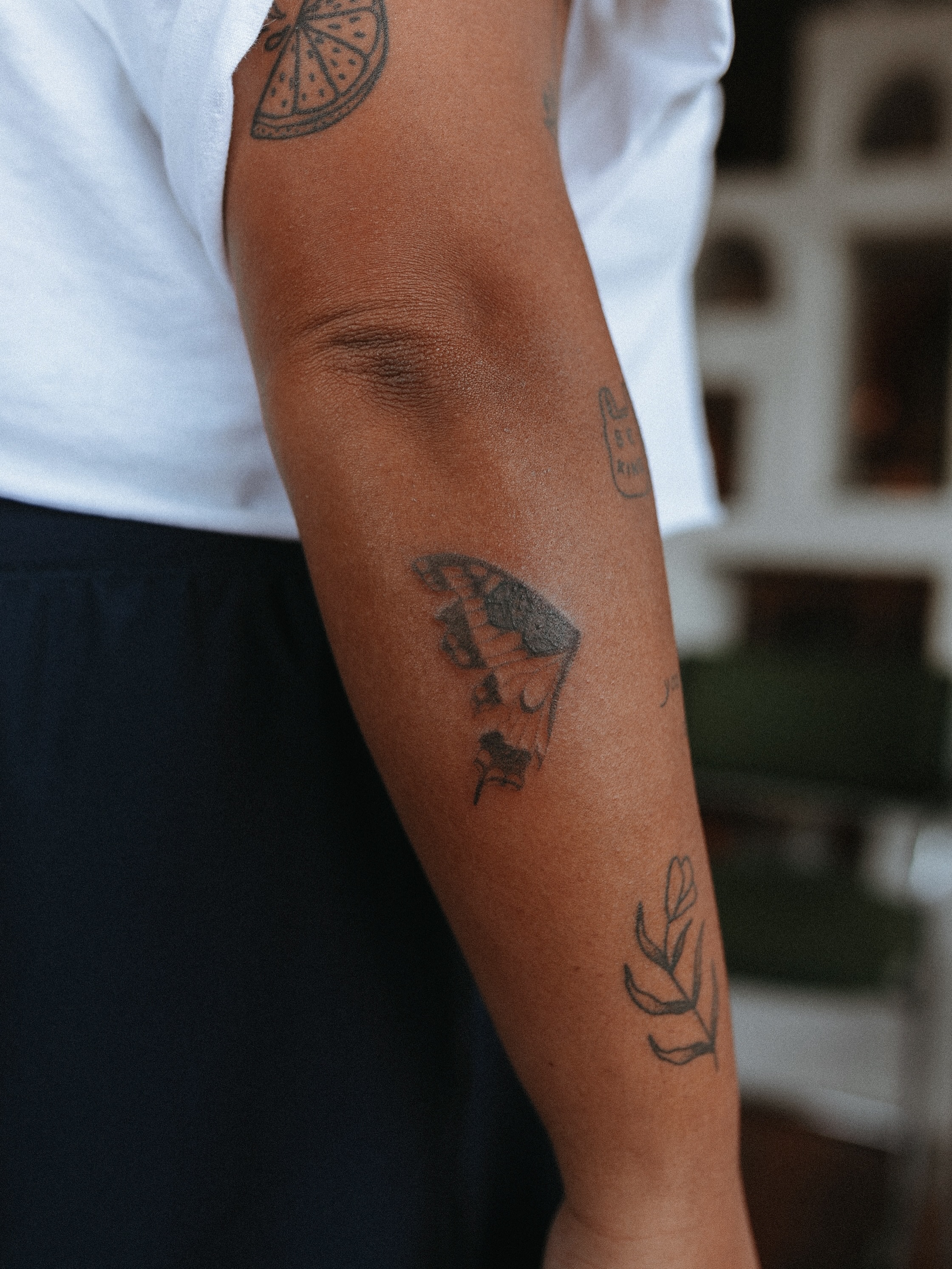 Butterfly and leaf black and grey tattoo on the forearm by Grace Wise - Handpoke Tattoos