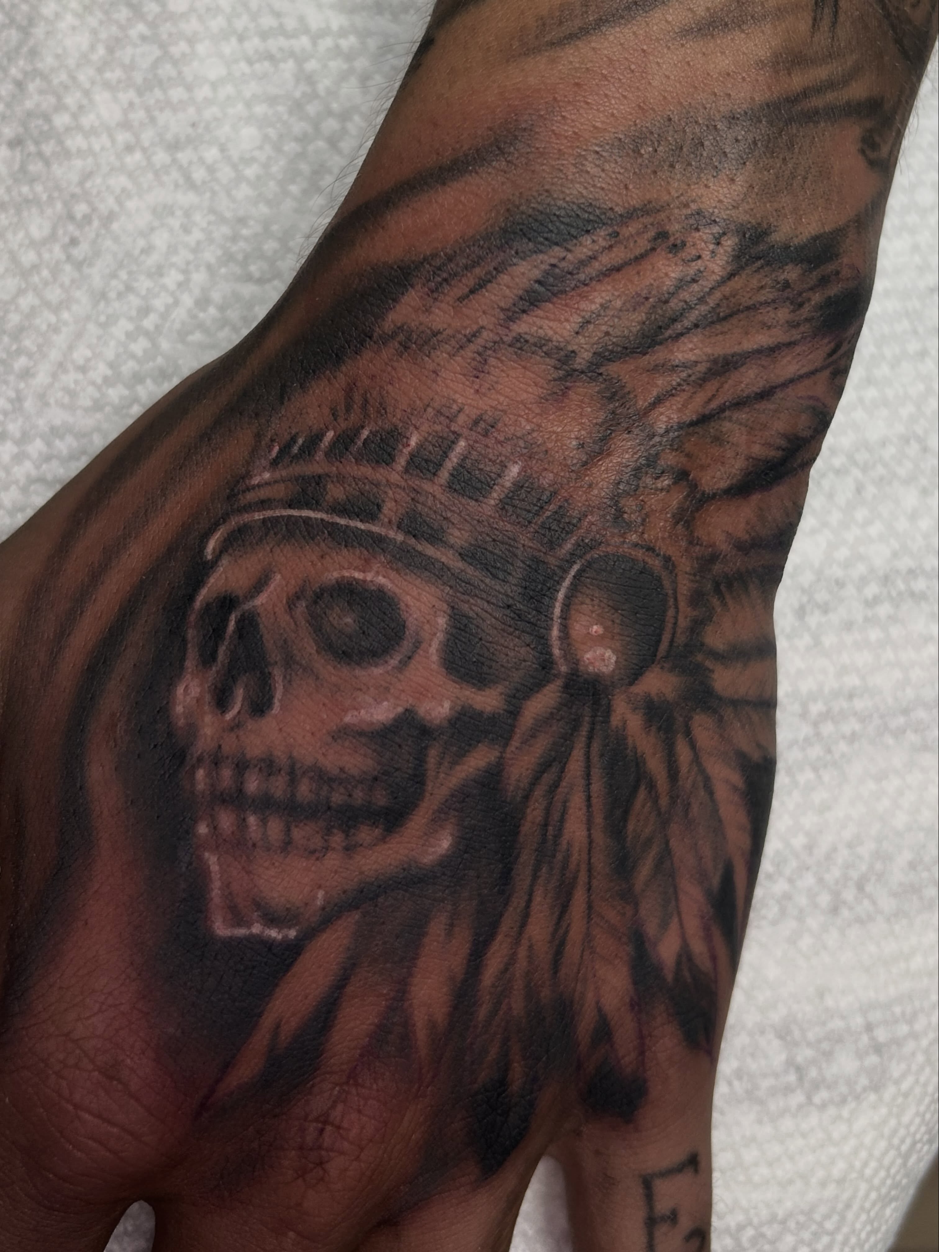 Skull with headdress realism tattoo on the hand by Dan Schuster