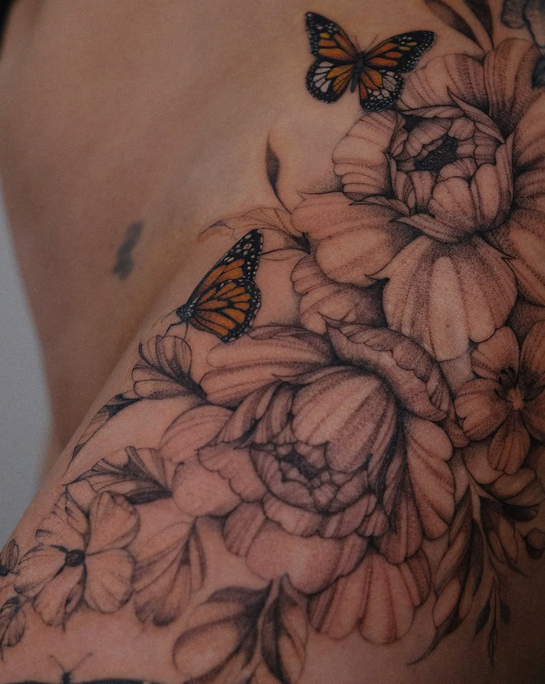 Monarch butterflies and flowers realism tattoo on the shoulder by Temple Adorned Tattoo