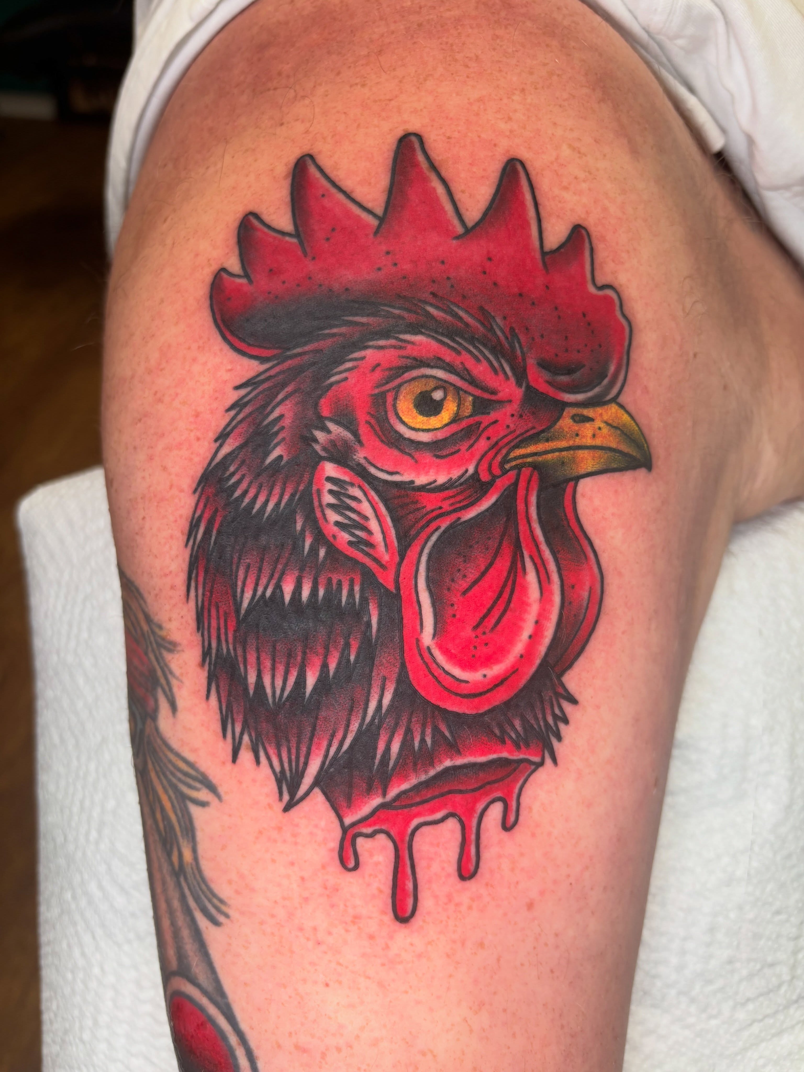 Rooster head American traditional tattoo on the upper arm by AARON MASTERS - Tattoo Artist