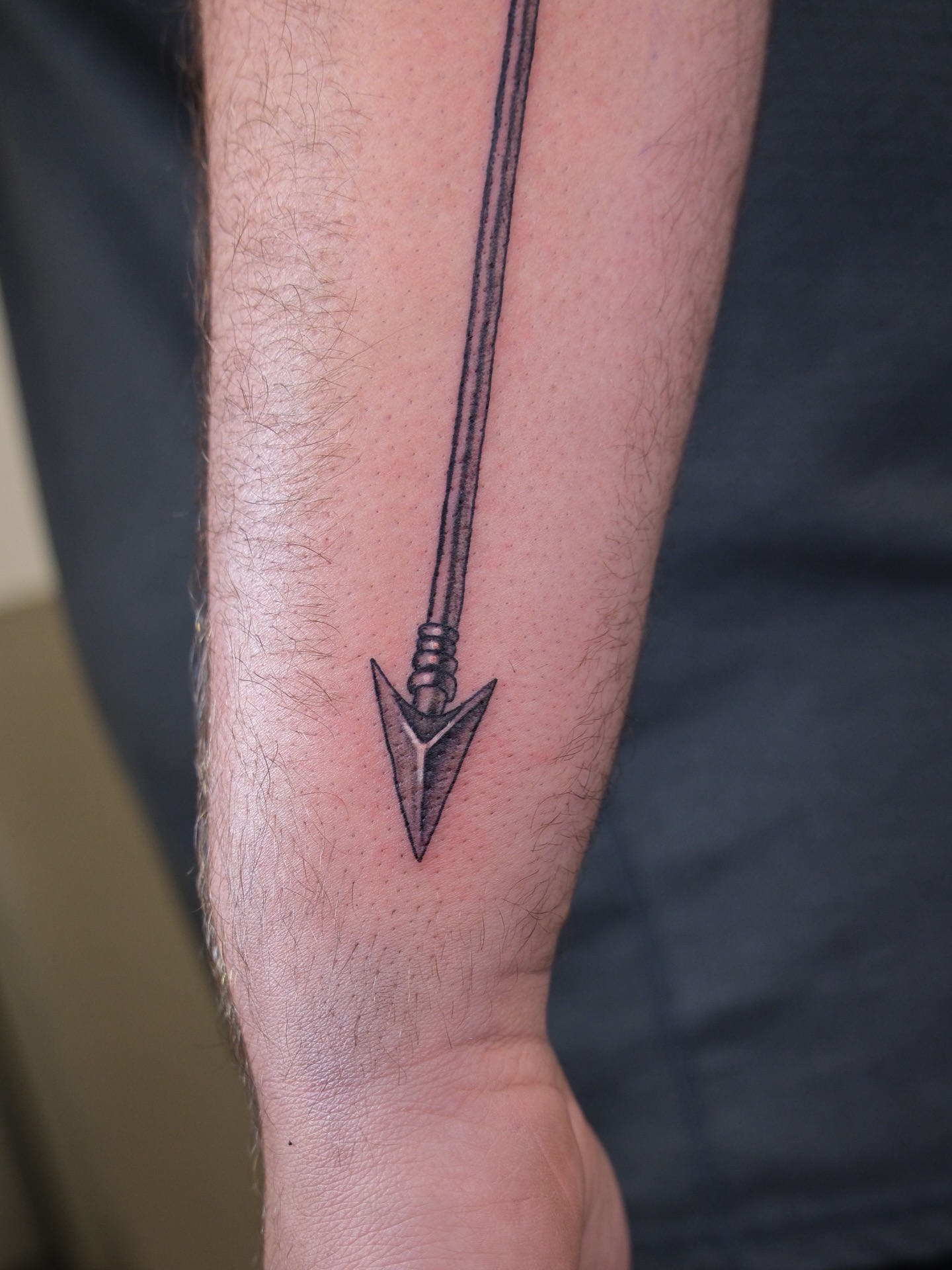 Arrow black and grey tattoo on the forearm by Kiana Hope