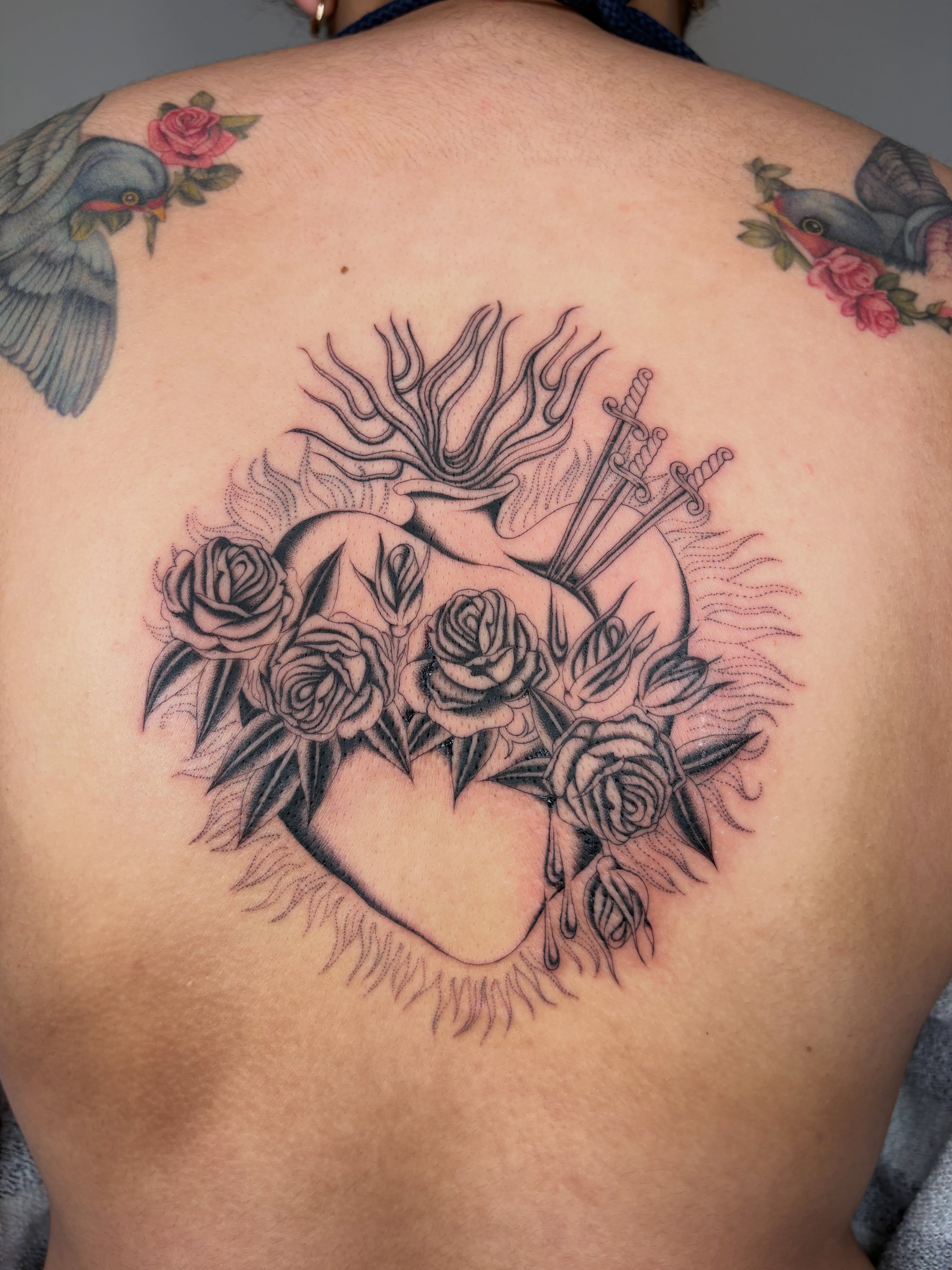 Heart with roses and swords black and grey tattoo on the back by Nori
