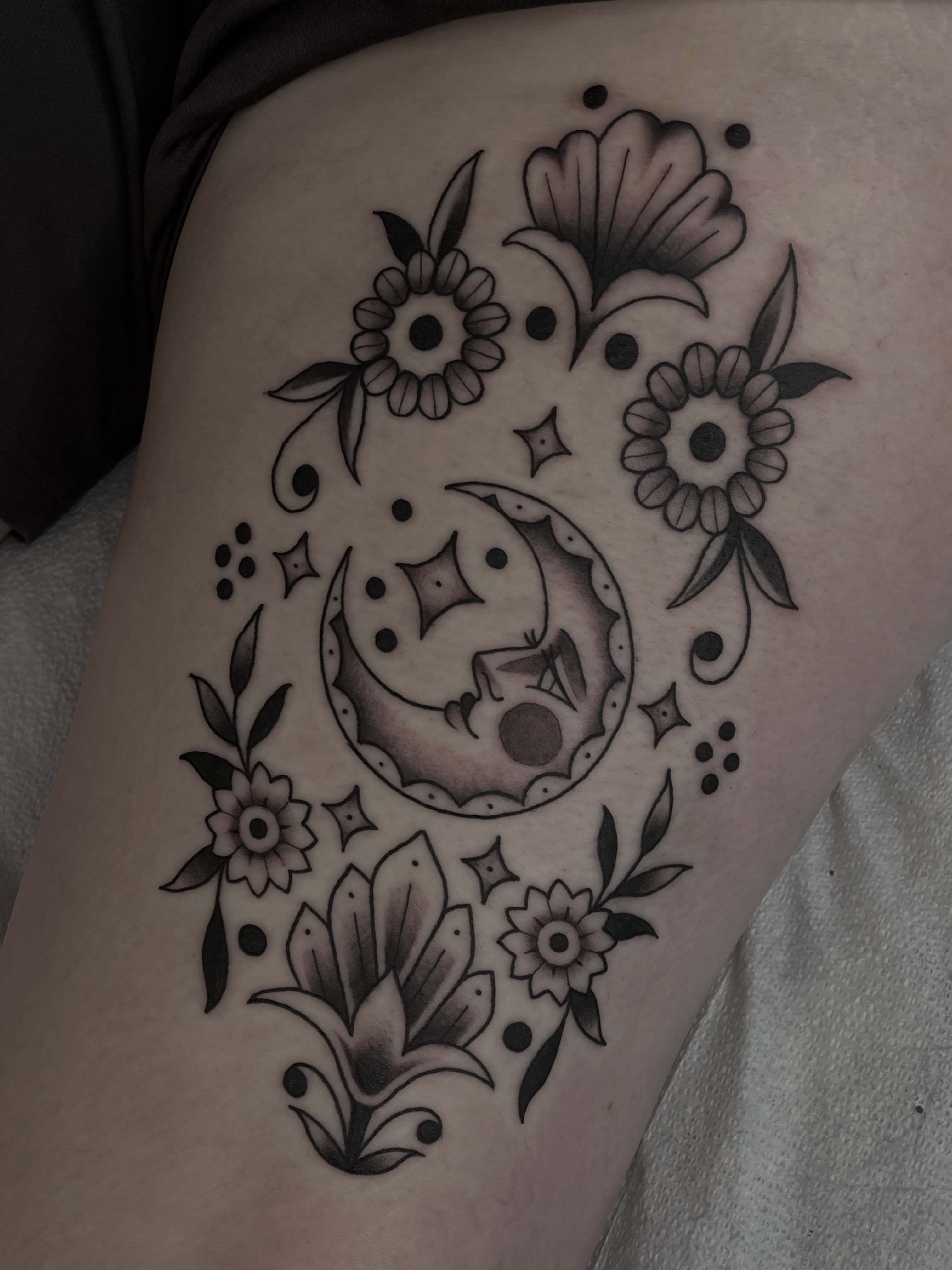 Moon and floral black and grey tattoo on the thigh by Amanda Marie, Edmonds, Washington