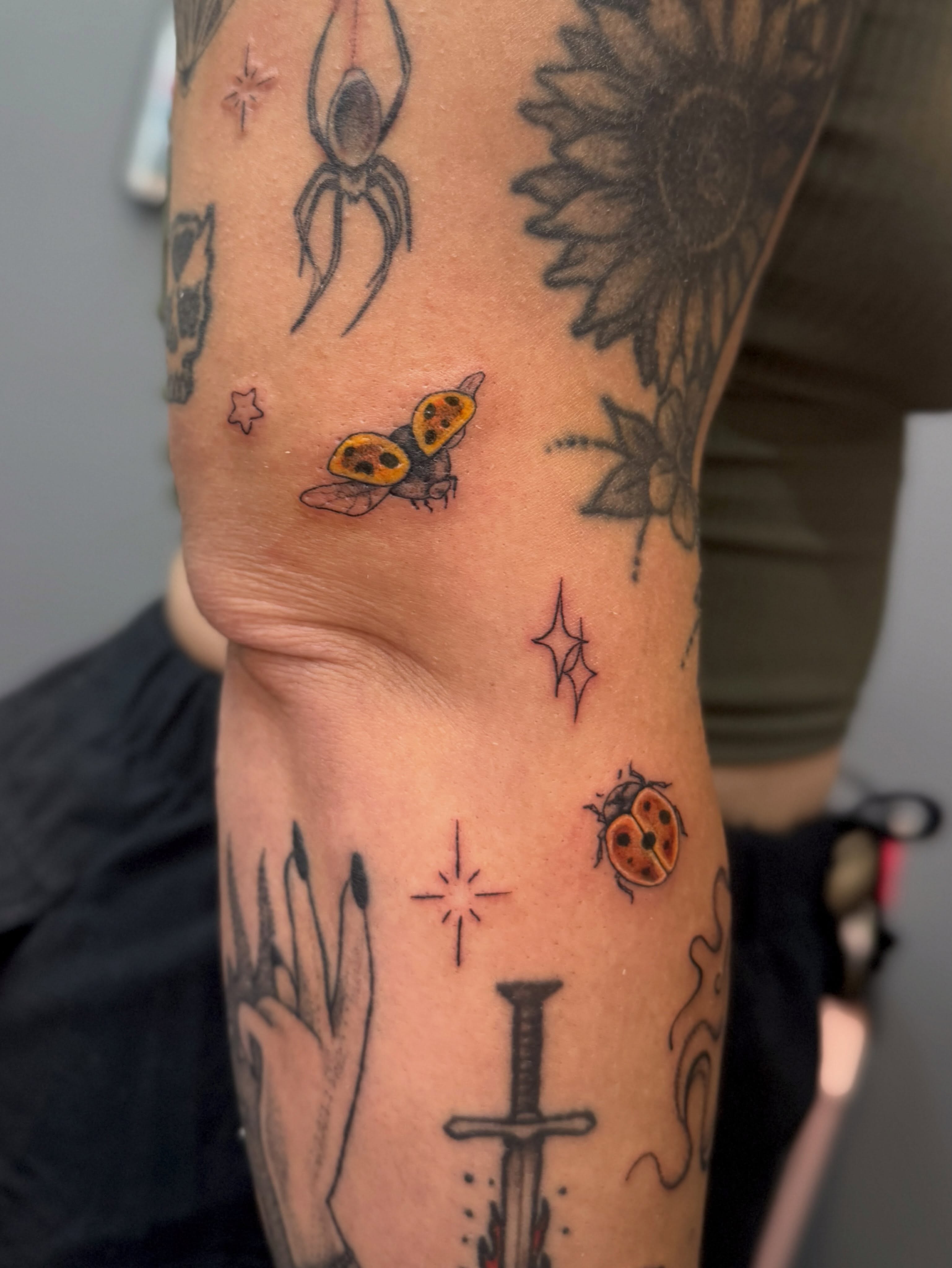Ladybugs and stars dotwork tattoo on the forearm by Kamakana Pankiwska